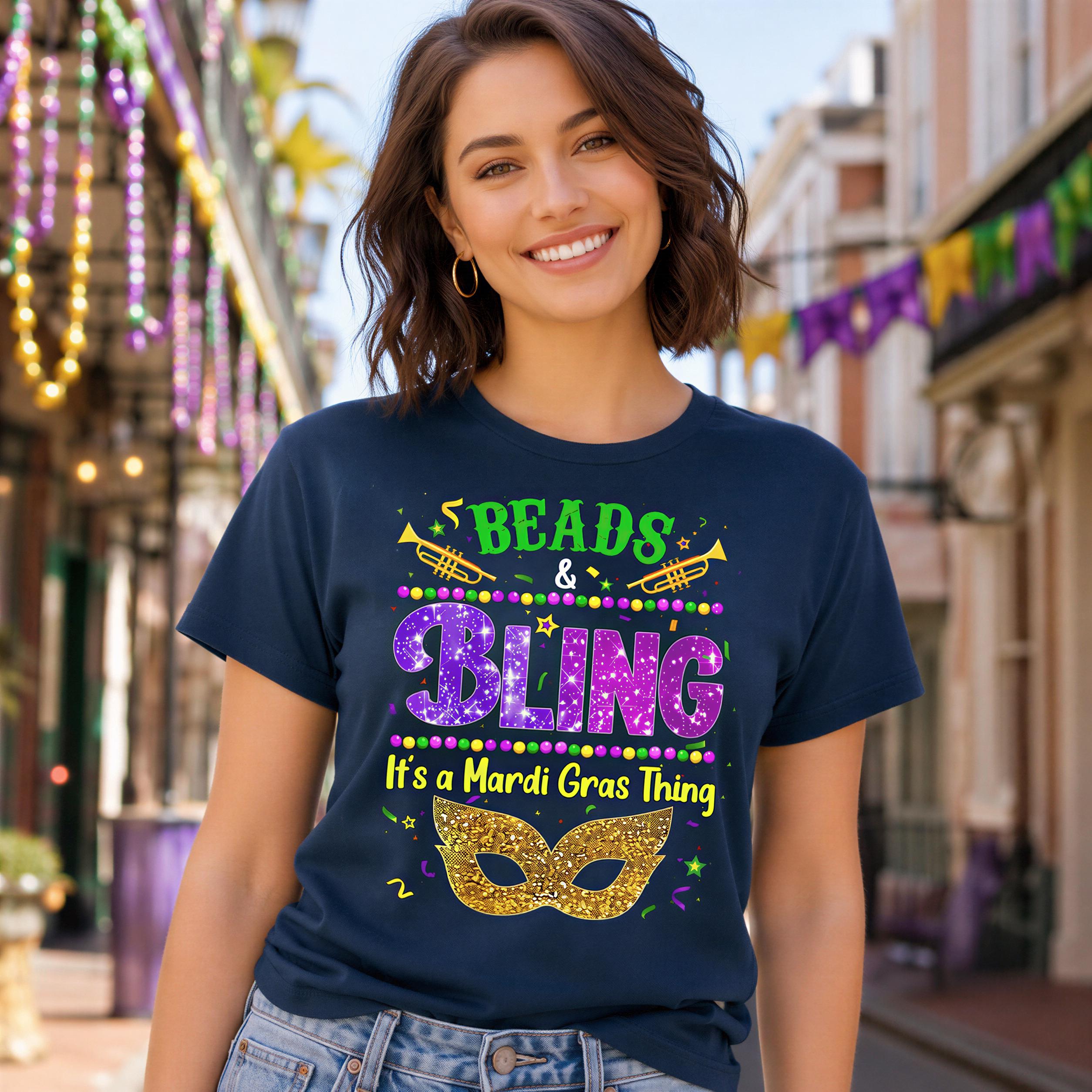 A woman wearing a blue t-shirt with text and graphics related to Mardi Gras, smiling at the camera.