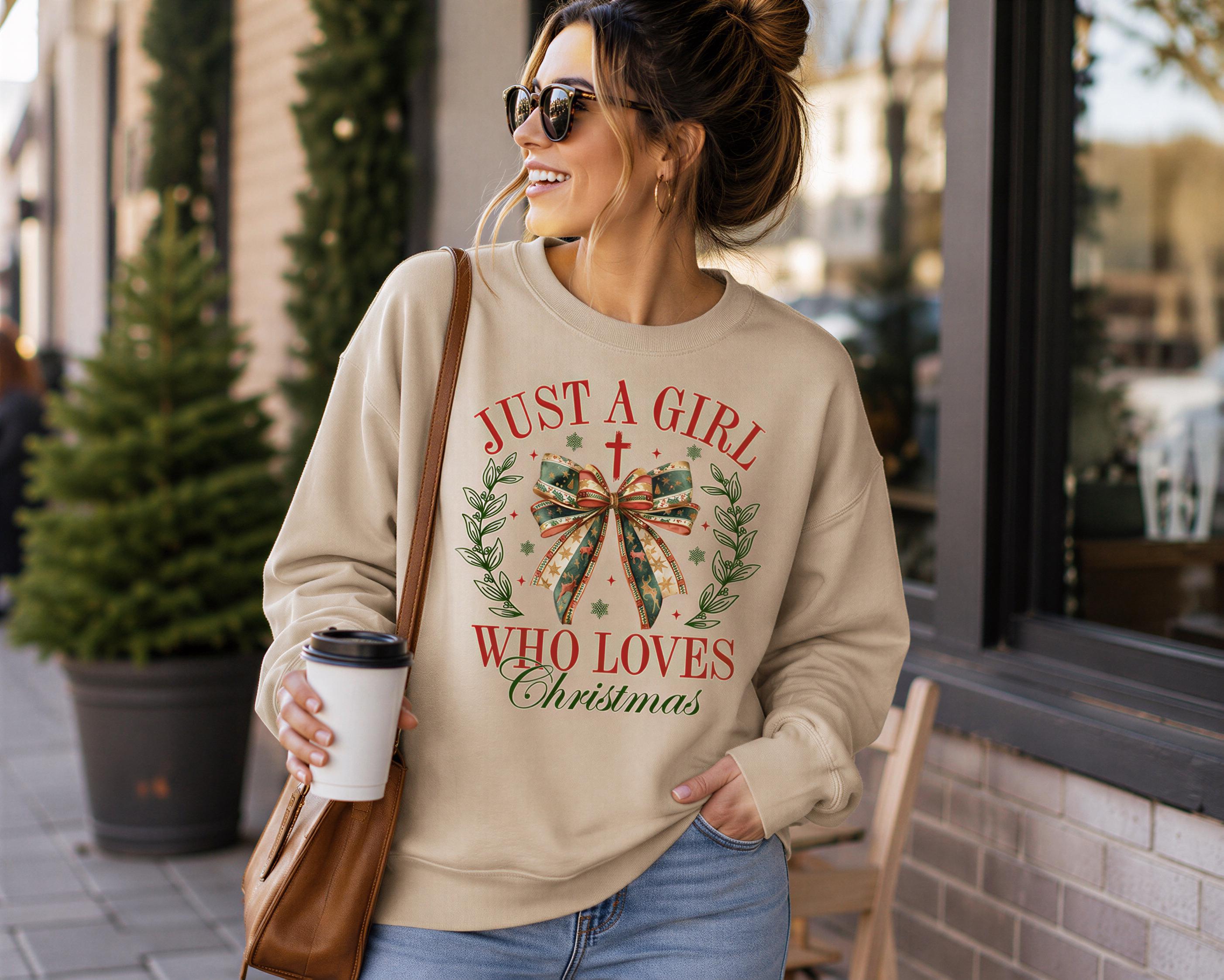 A woman wearing a beige sweater with a Christmas-themed design and holding a coffee cup is standing in front of a building.