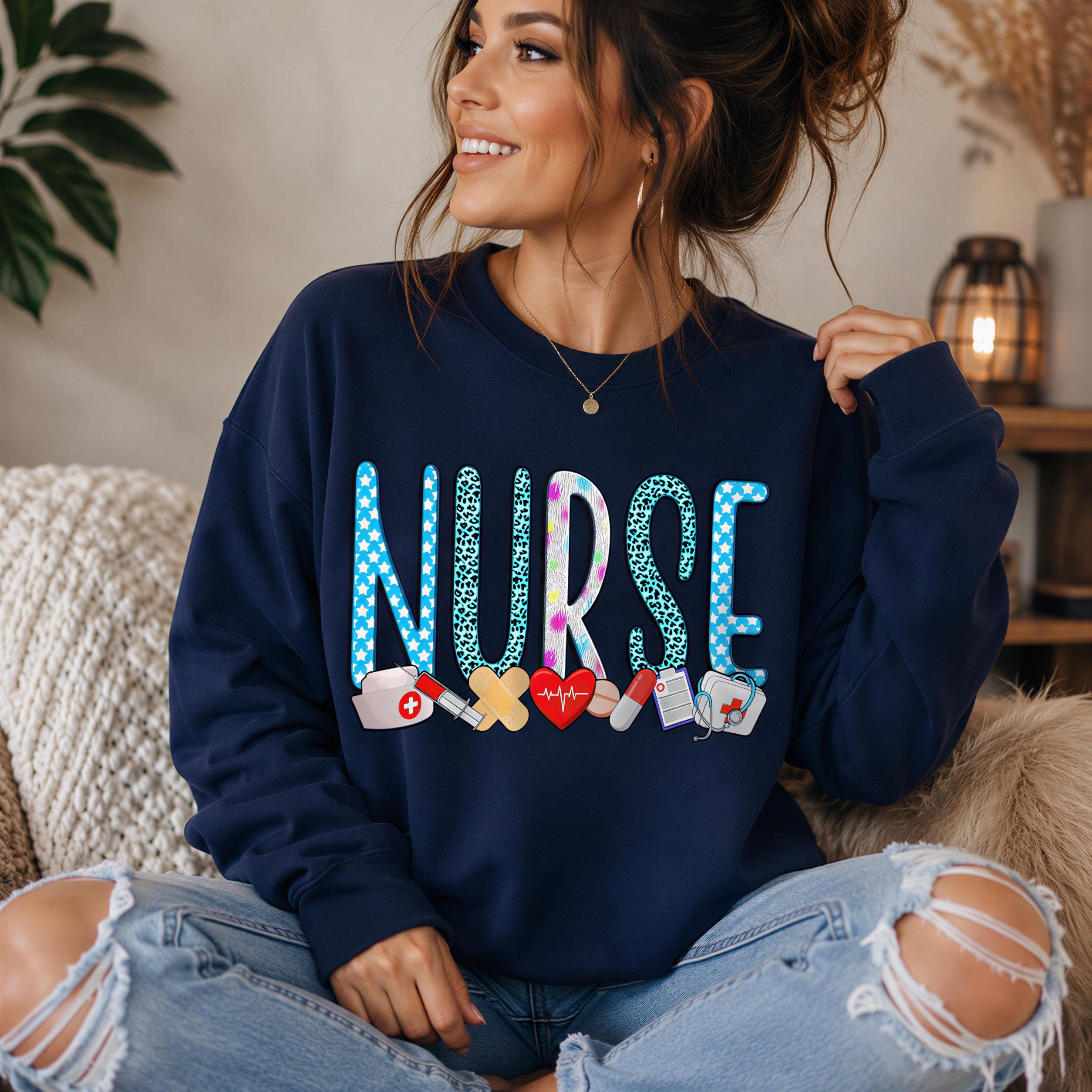 A woman wearing a navy blue sweatshirt with the word "NURSE" printed on it, sitting on a couch and smiling.