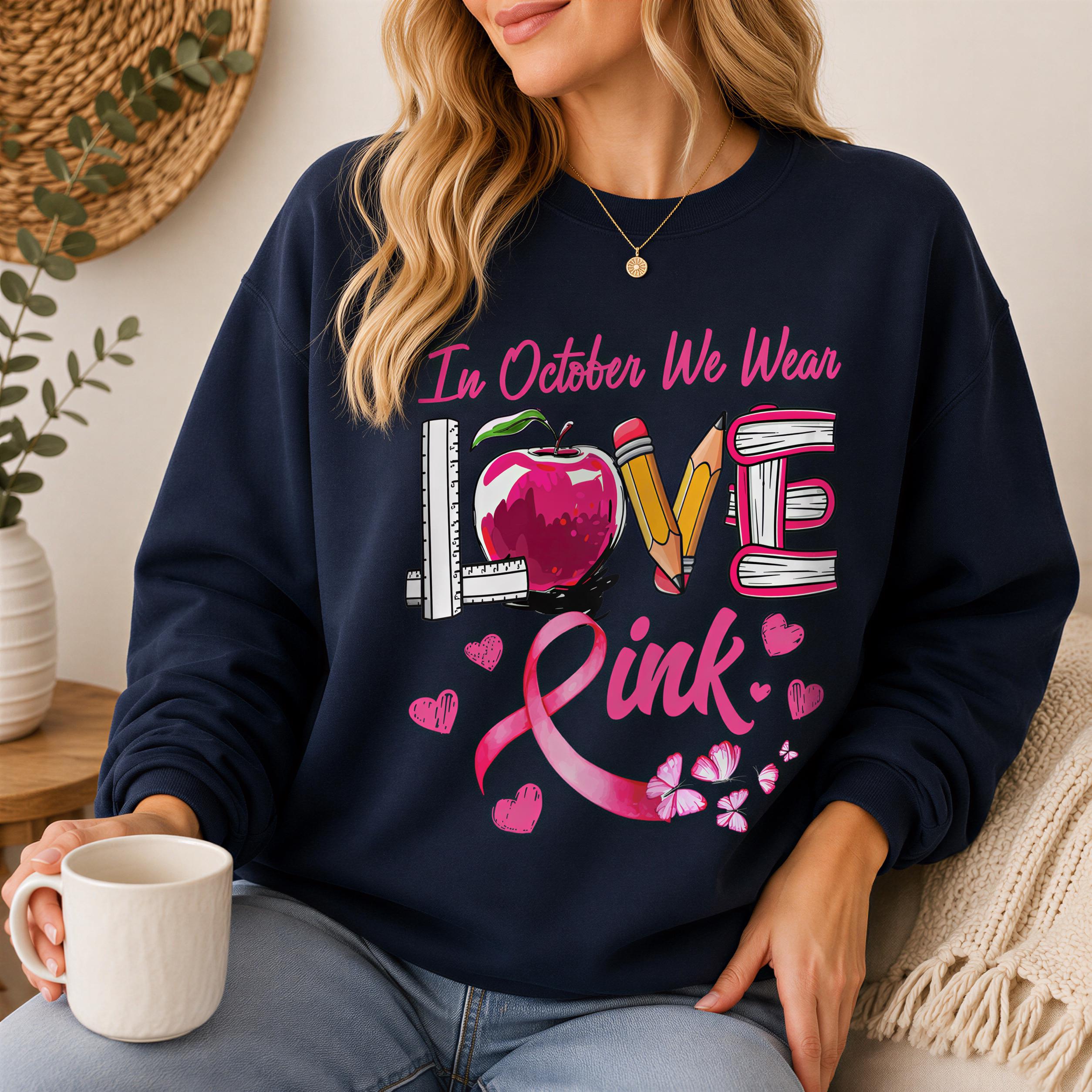A woman wearing a navy blue sweatshirt with a pink ribbon design and text printed on it.