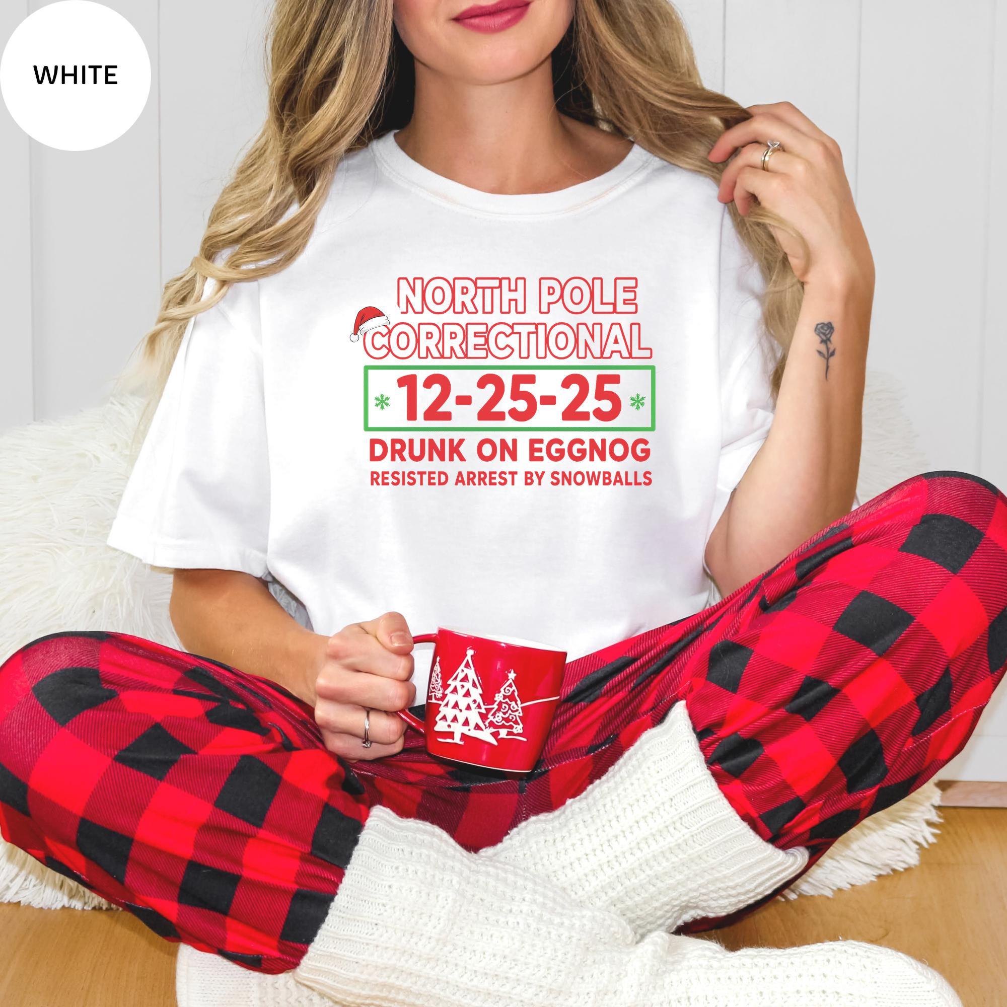A woman wearing a white t-shirt with text and a mug in her hand, sitting on the floor.