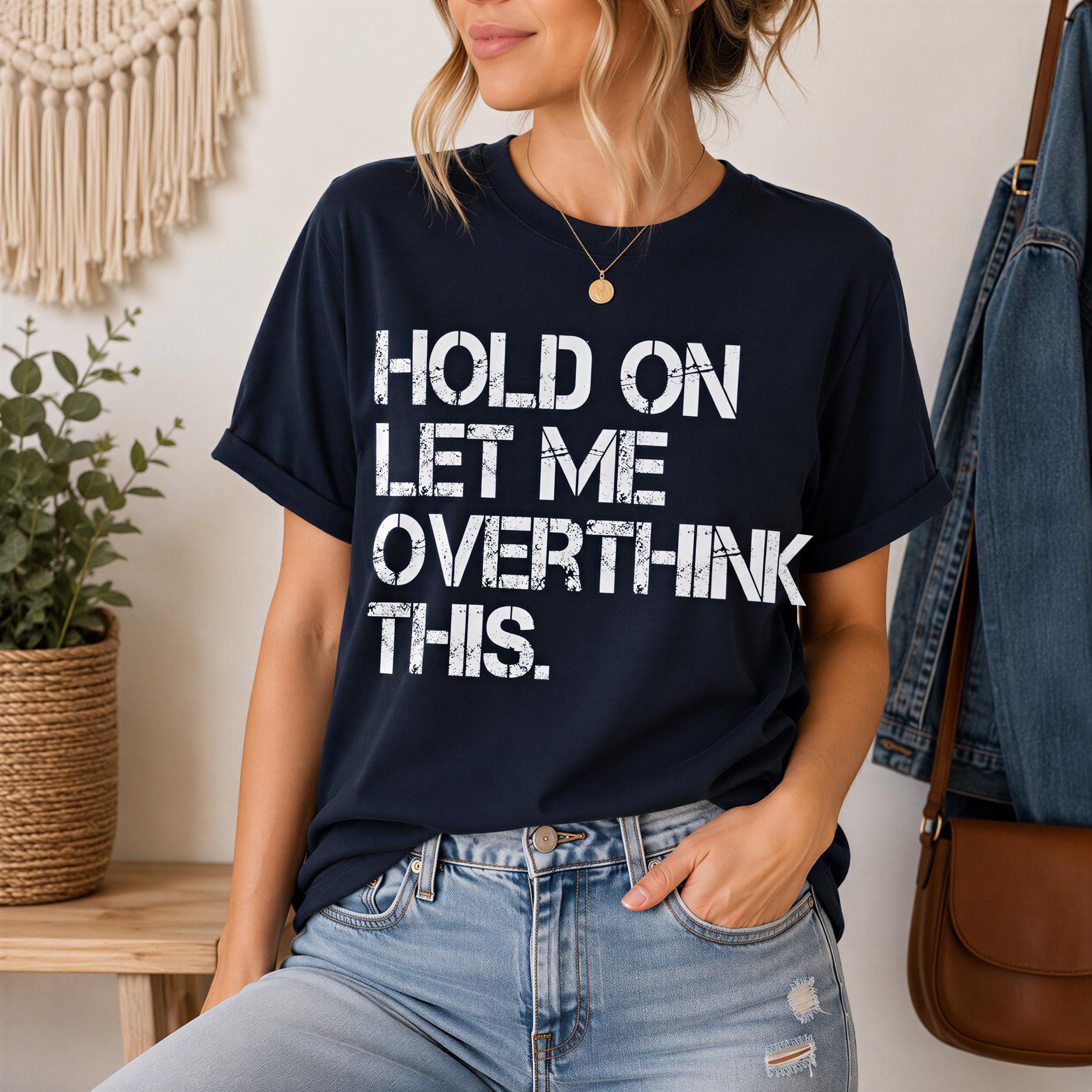 A woman wearing a navy blue t-shirt with the text "HOLD ON LET ME OVERTHINK THIS" printed on it.