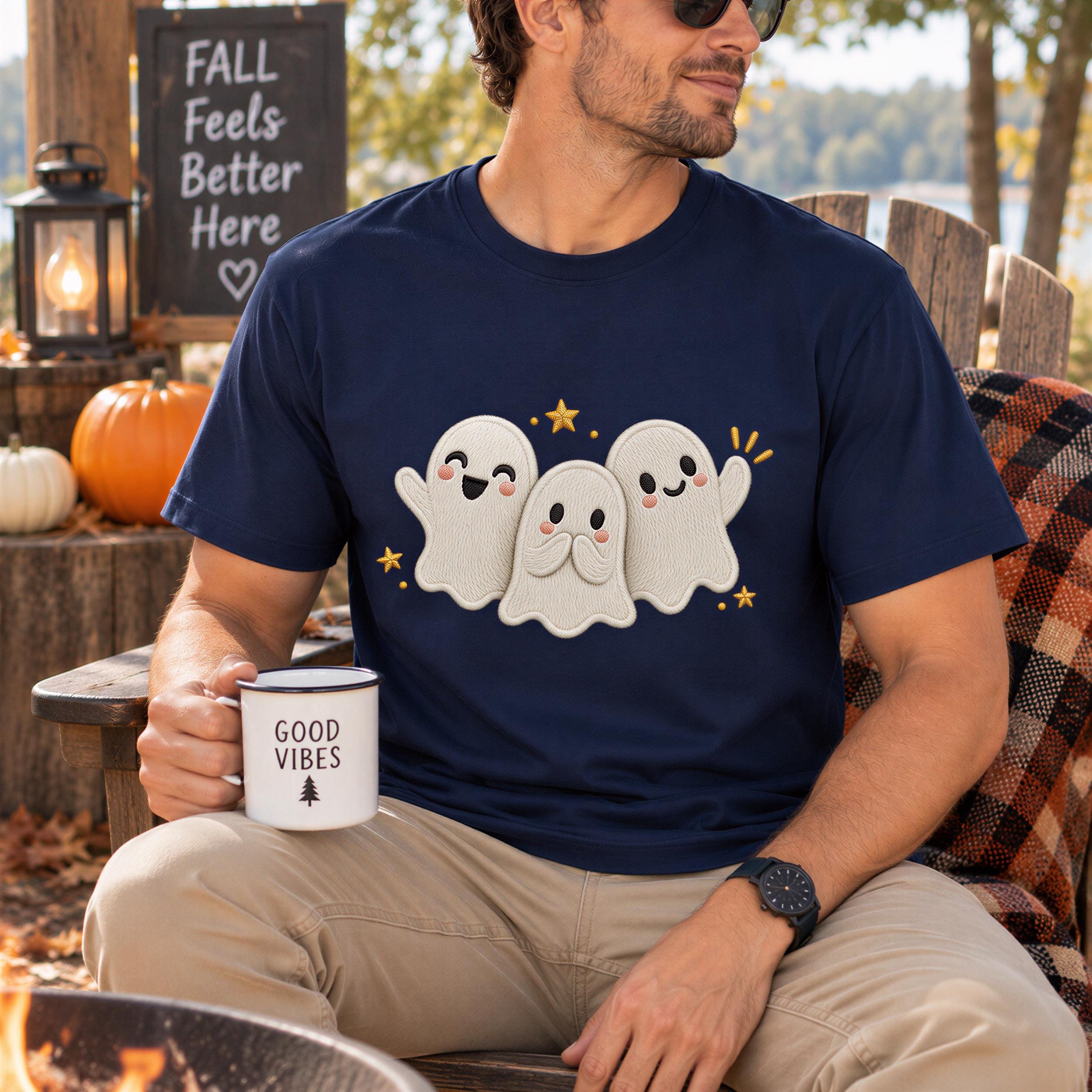 A man wearing a navy blue t-shirt with a graphic of three smiling ghost characters is sitting in a chair, holding a coffee mug with the words "Good Vibes" printed on it.