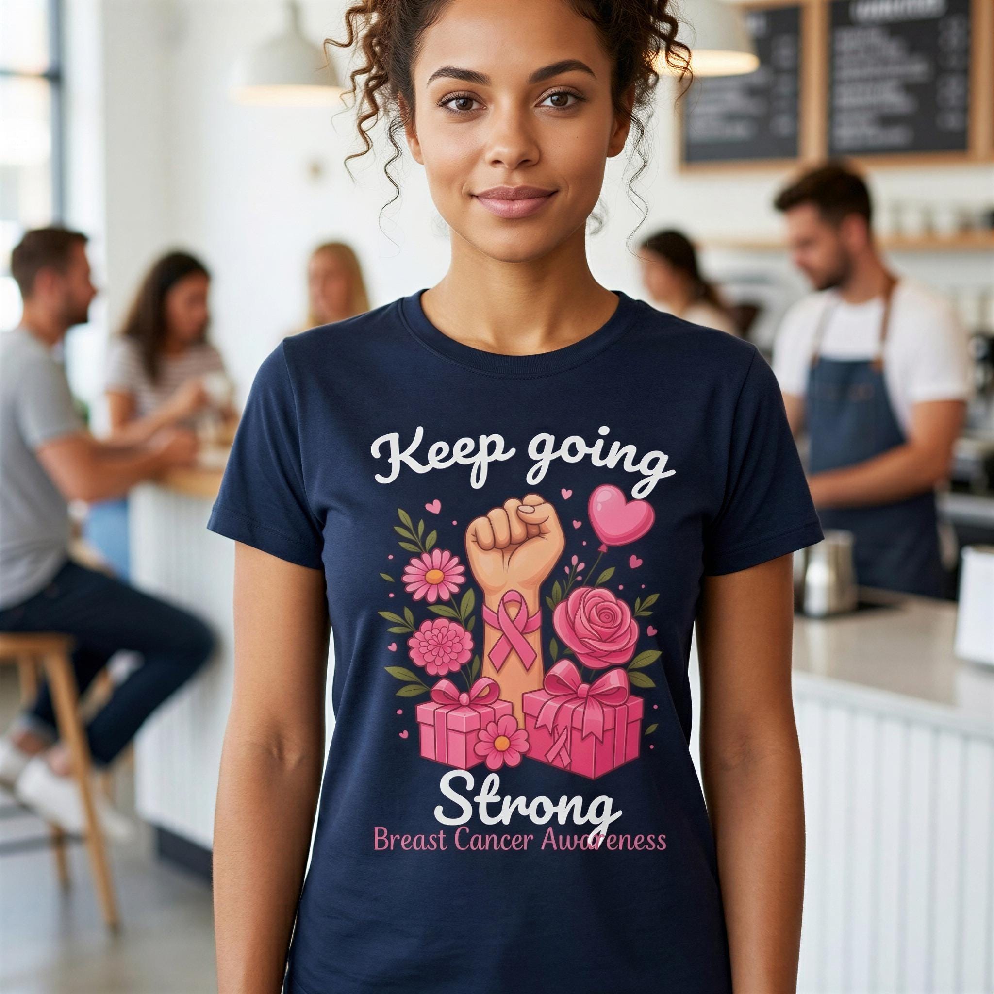 A woman wearing a navy blue t-shirt with a graphic design related to breast cancer awareness, including a fist symbol, flowers, and pink ribbon.