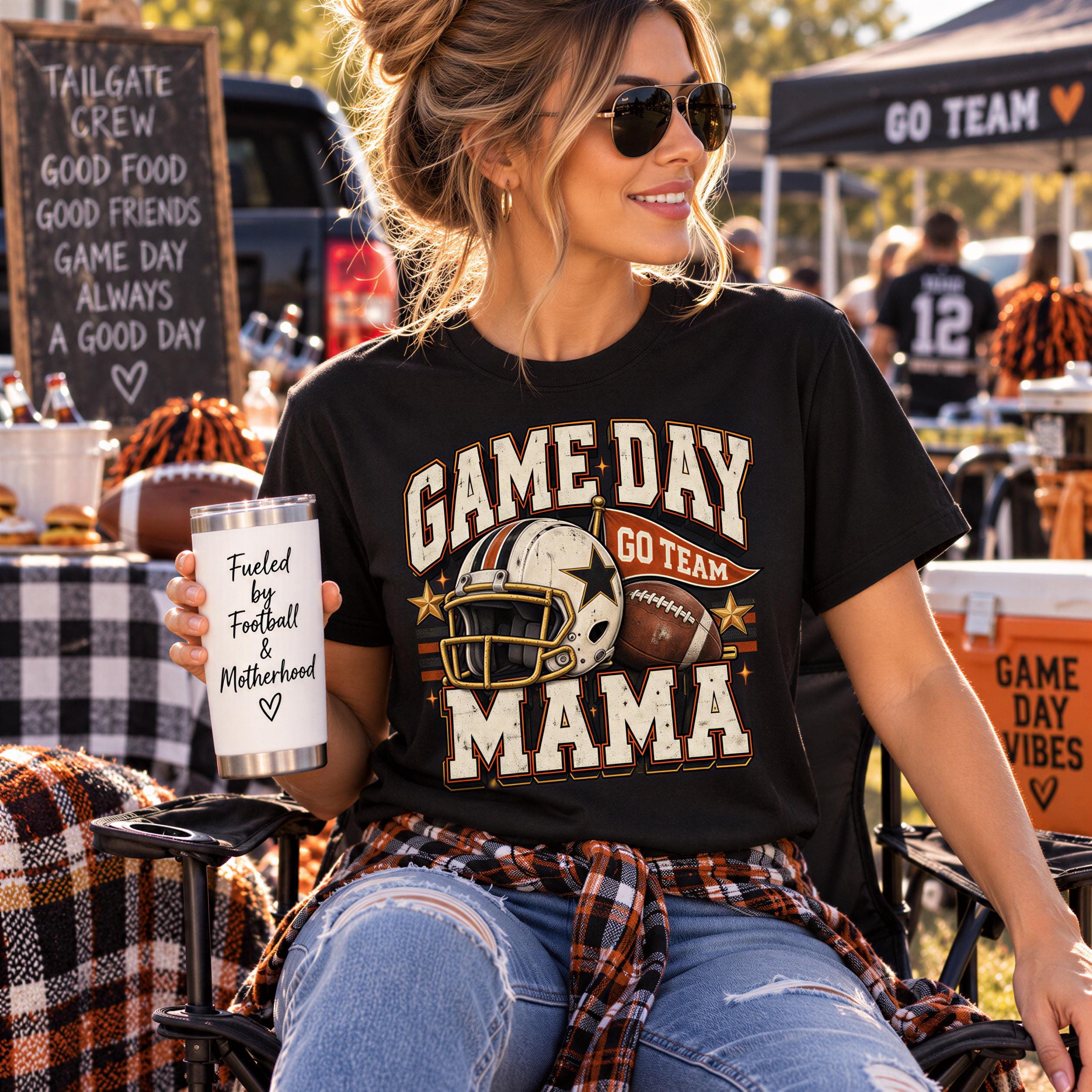 A woman wearing a black t-shirt with a football helmet and the text "GAME DAY GO TEAM MAMA" is sitting in a chair at an outdoor event, holding a white cup with the text "Fuelled by Football and Motherhood".