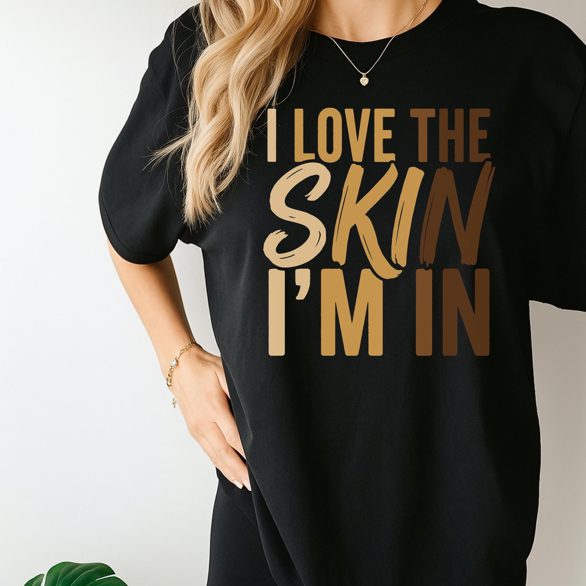 A person wearing a black t-shirt with the text "I LOVE THE SKIN I'M IN" printed on it.