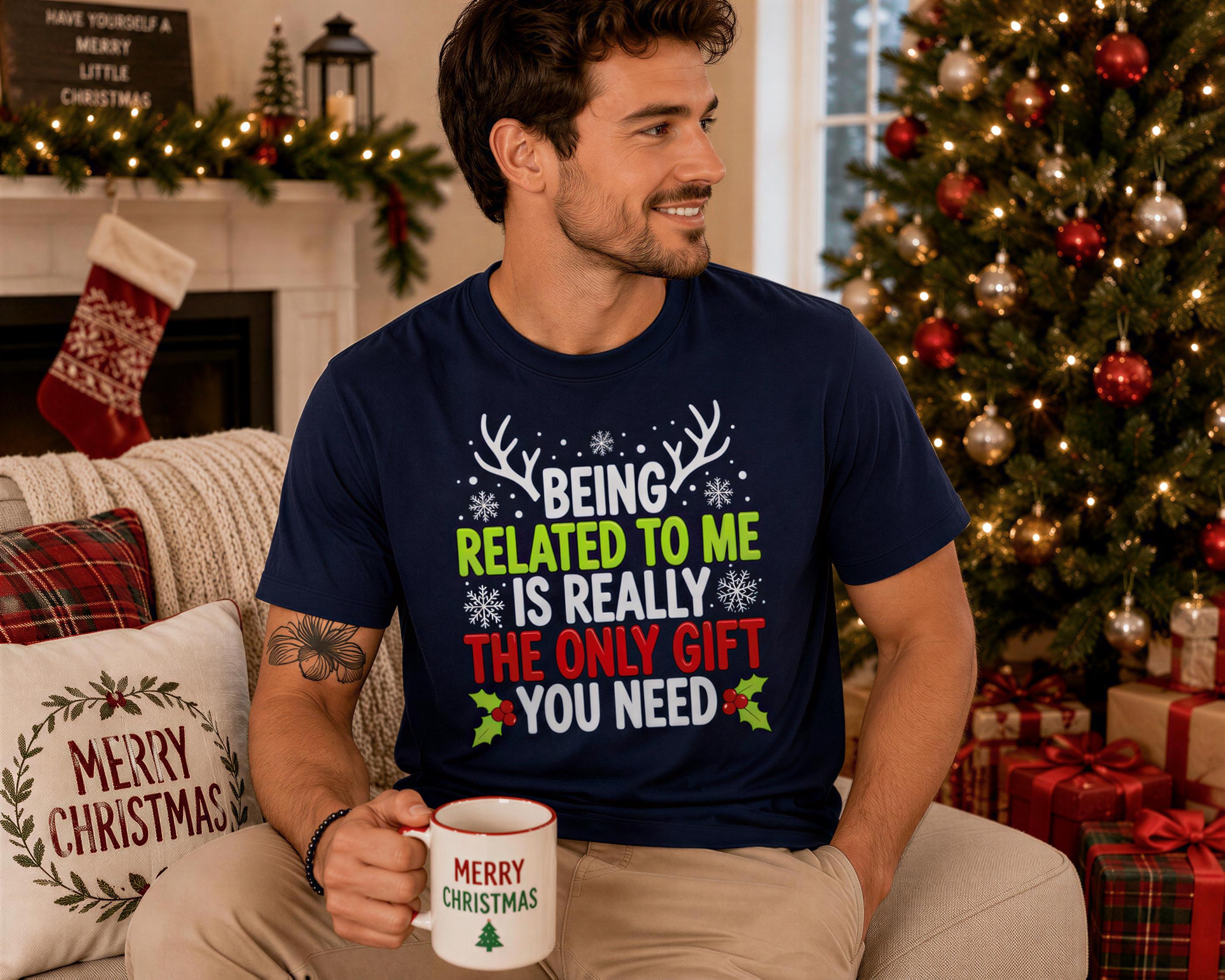 A man wearing a blue t-shirt with text and a Christmas tree in the background.