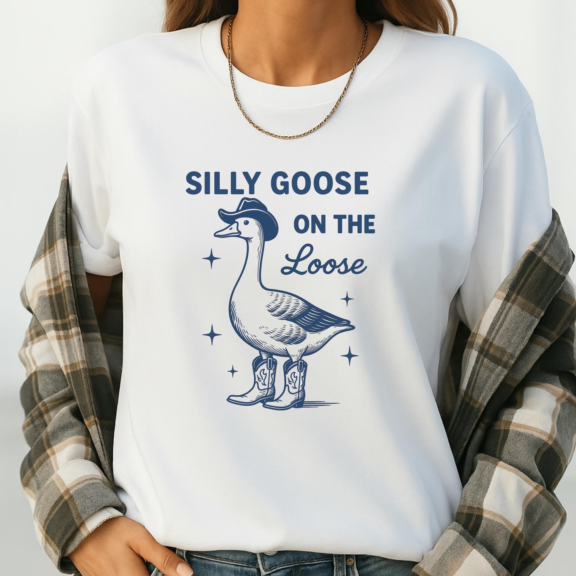 A white t-shirt with a graphic design of a goose wearing a cowboy hat and boots, along with the text "Silly Goose on the Loose".