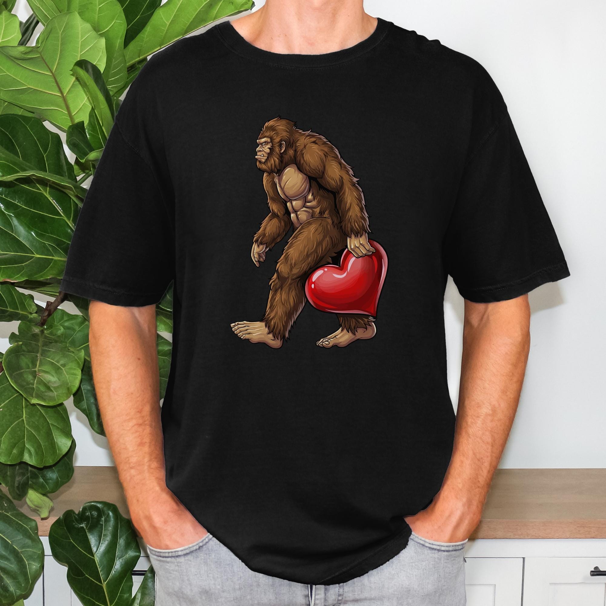 A man wearing a black t-shirt with a graphic of a brown gorilla holding a red heart.