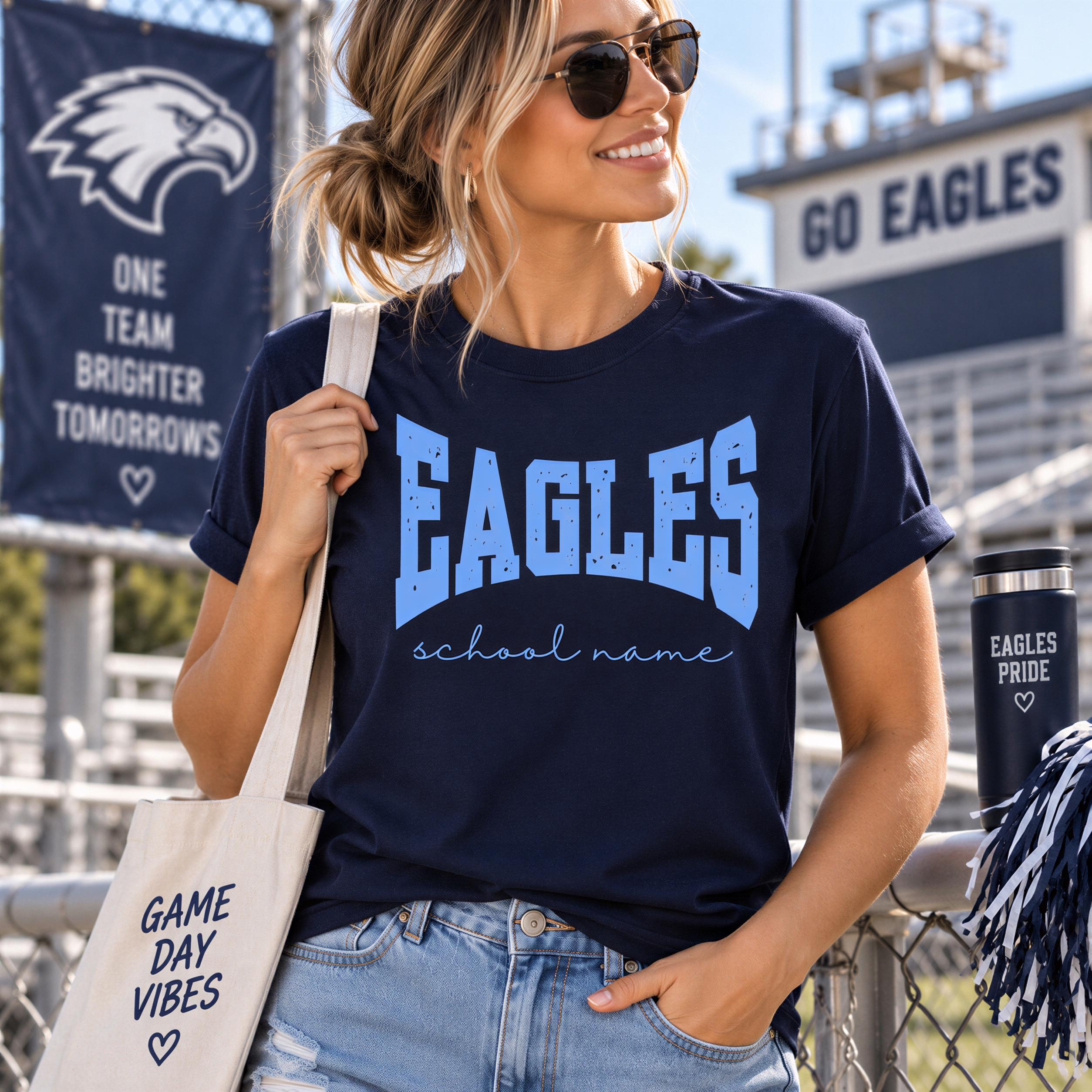 A woman wearing a navy blue Eagles t-shirt and sunglasses stands in front of a stadium, holding a white tote bag with the text "GAME DAY VIBES" printed on it.