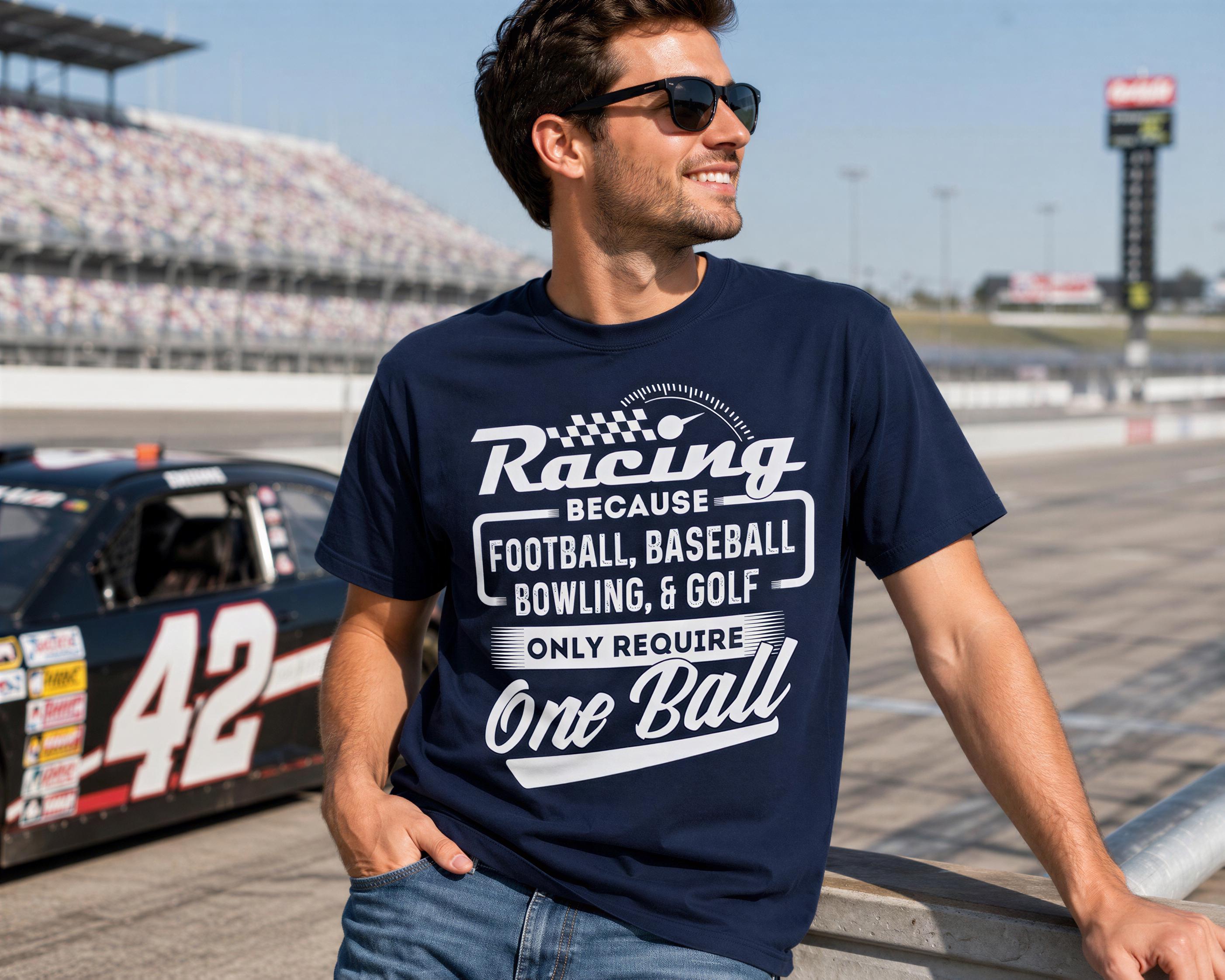 A man wearing a navy blue t-shirt with white text and graphics stands next to a race car on a racetrack.