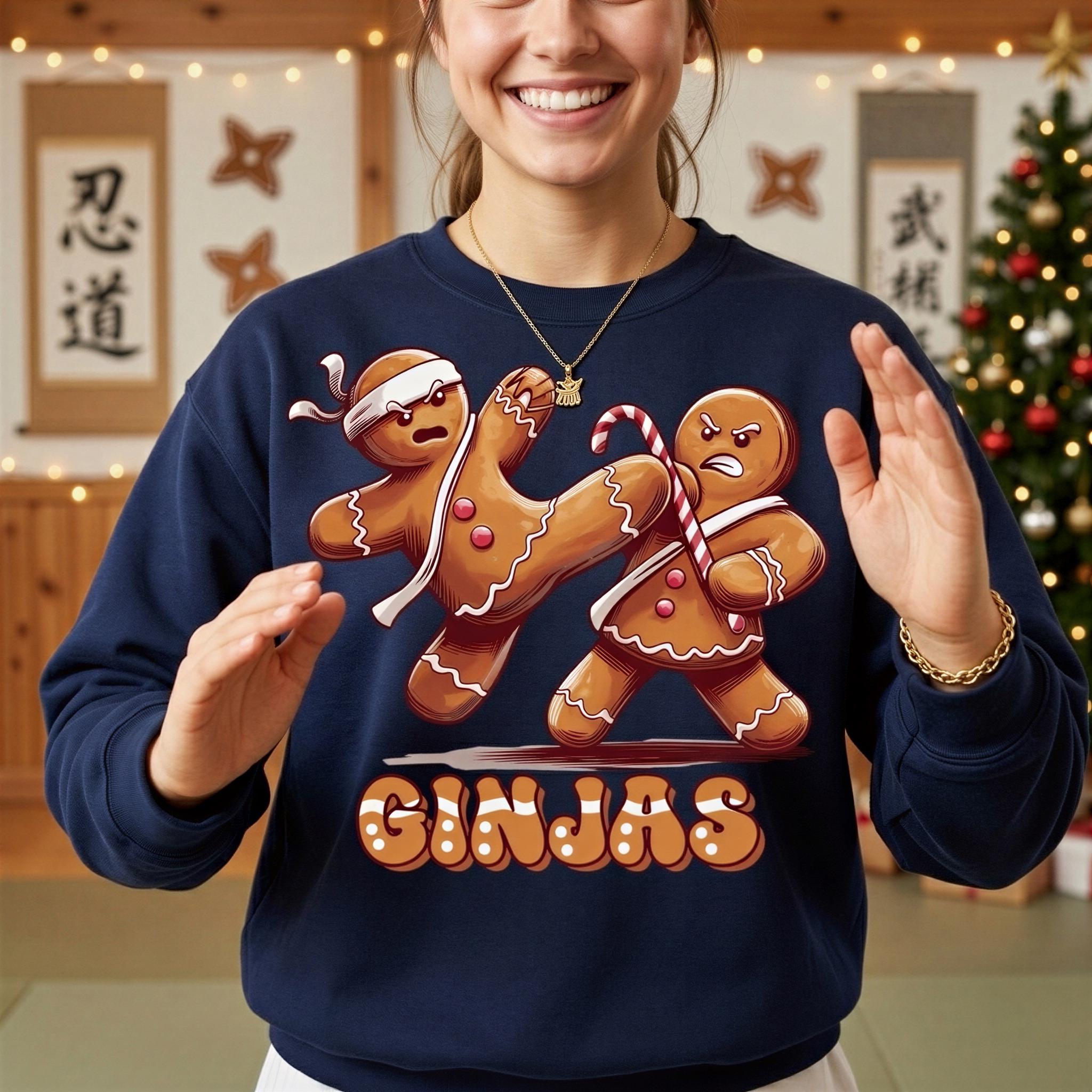 A woman wearing a navy blue sweatshirt with a graphic of two gingerbread men engaged in a fight, with one gingerbread man appearing to kick the other. The word "GINJAS" is written below the image.