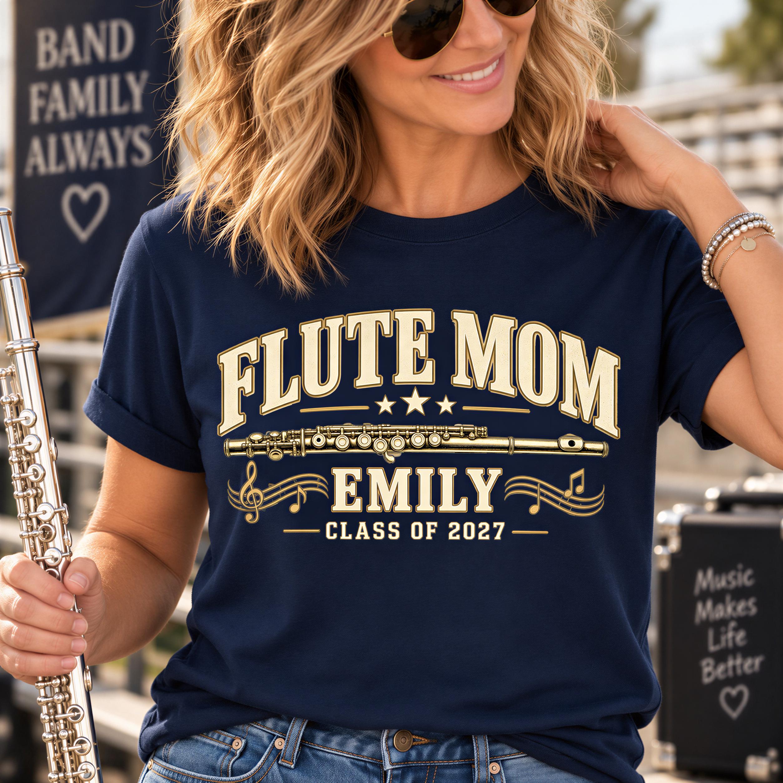 A woman wearing a navy blue t-shirt with a graphic design that says "FLUTE MOM EMILY CLASS OF 2027" and holding a silver flute.