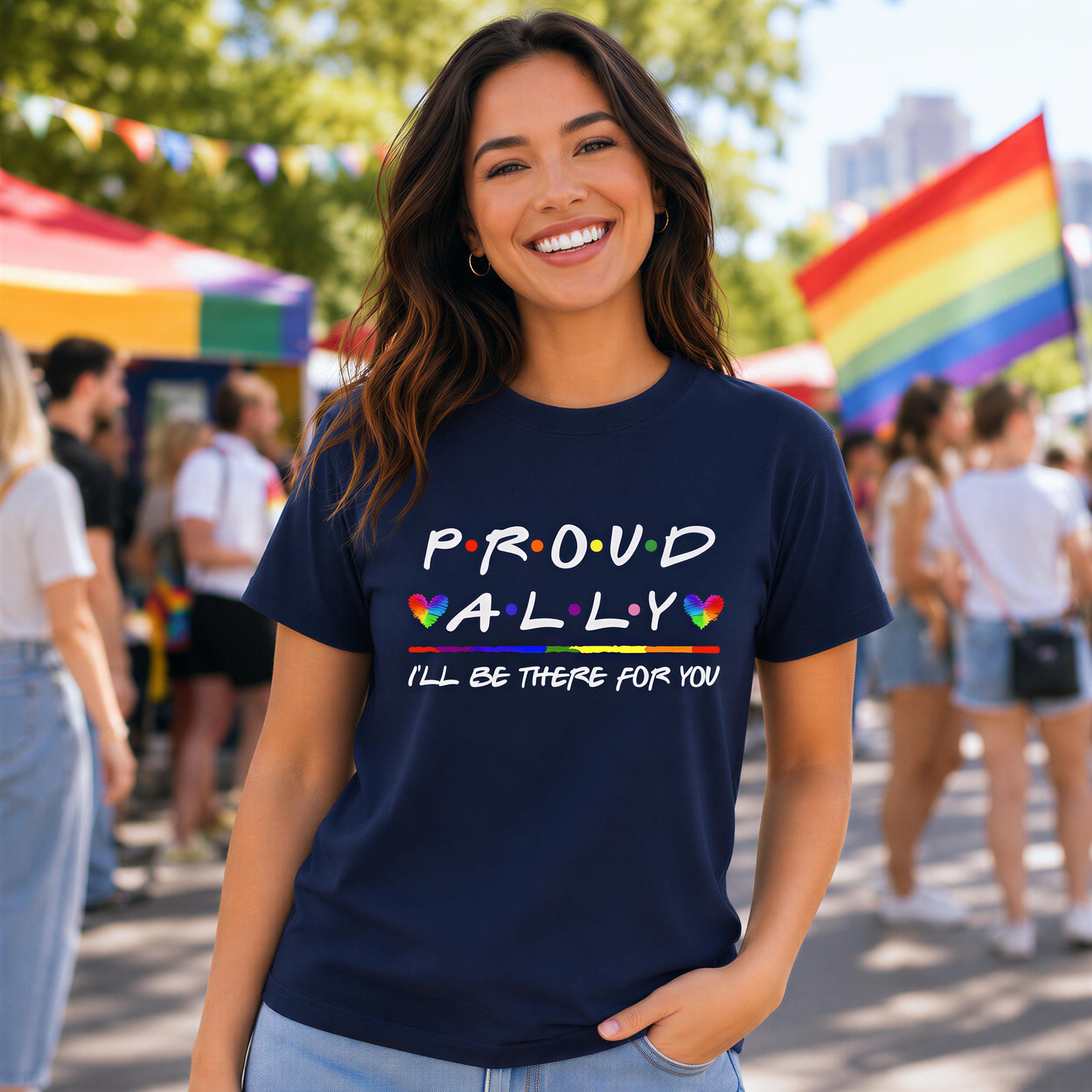 A woman wearing a navy blue t-shirt with the text "Proud Ally I'll be there for you" is smiling at the camera.