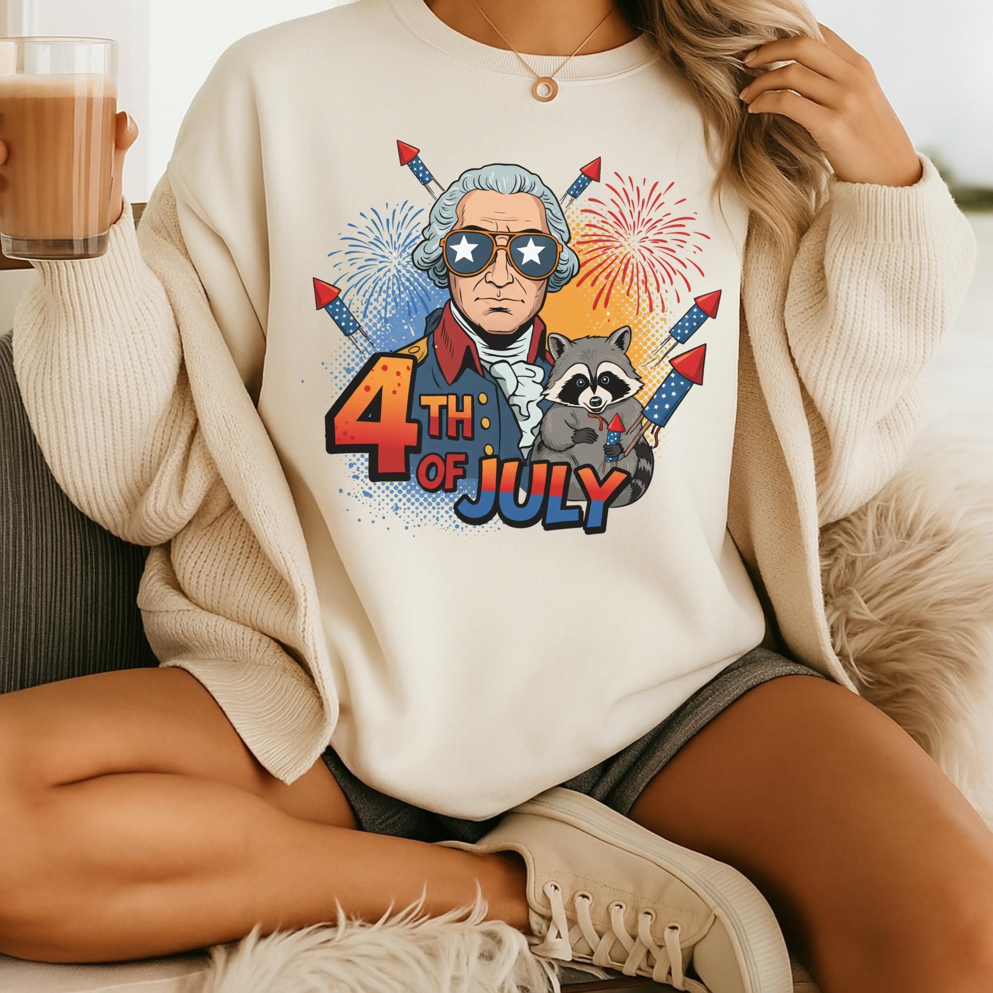 A person wearing a white sweater with a graphic design featuring a cartoon character and fireworks, holding a drink.