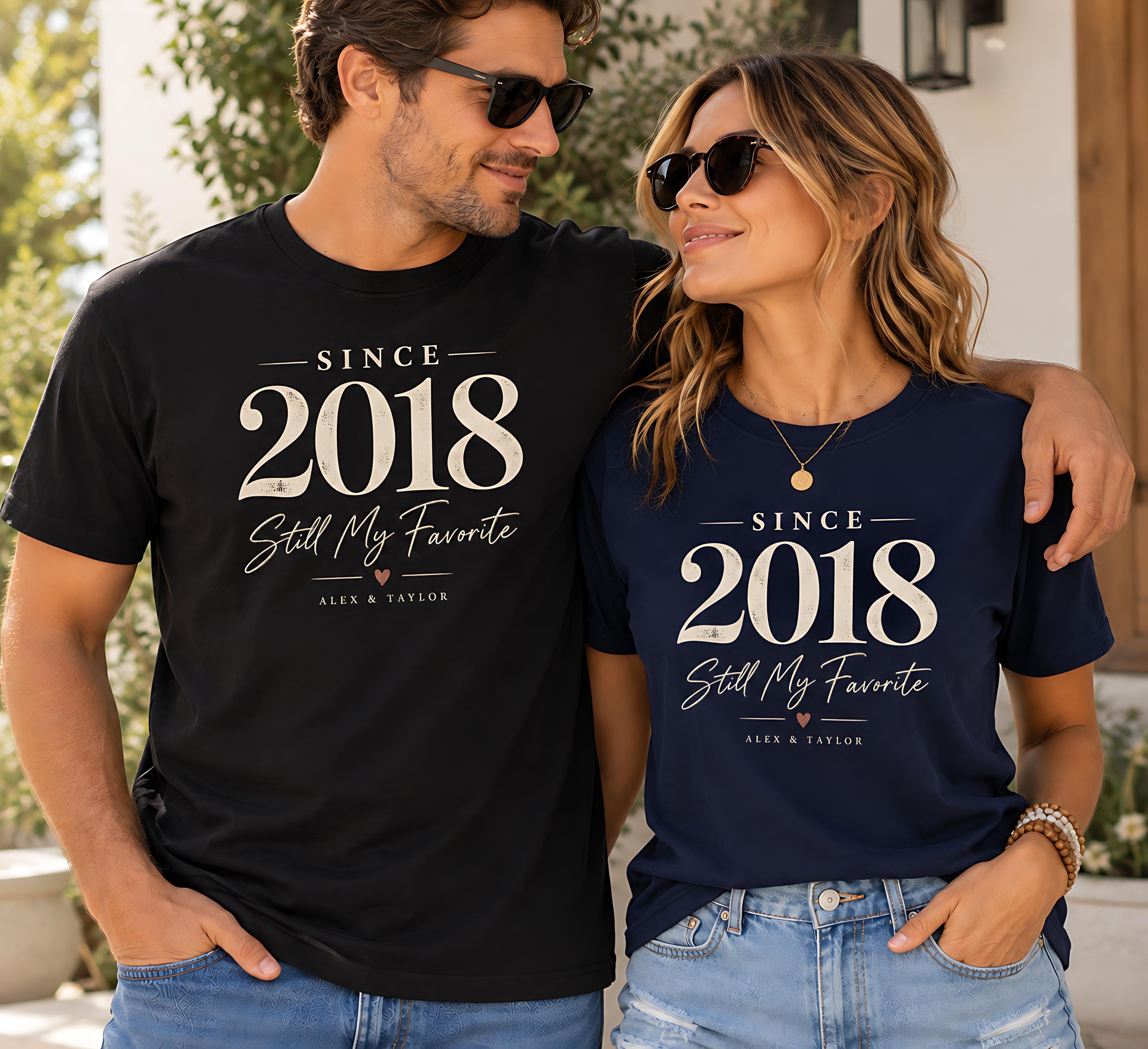 A man and a woman standing together, both wearing matching t-shirts with the text "SINCE 2018 Still My Favorite Alex & Taylor".