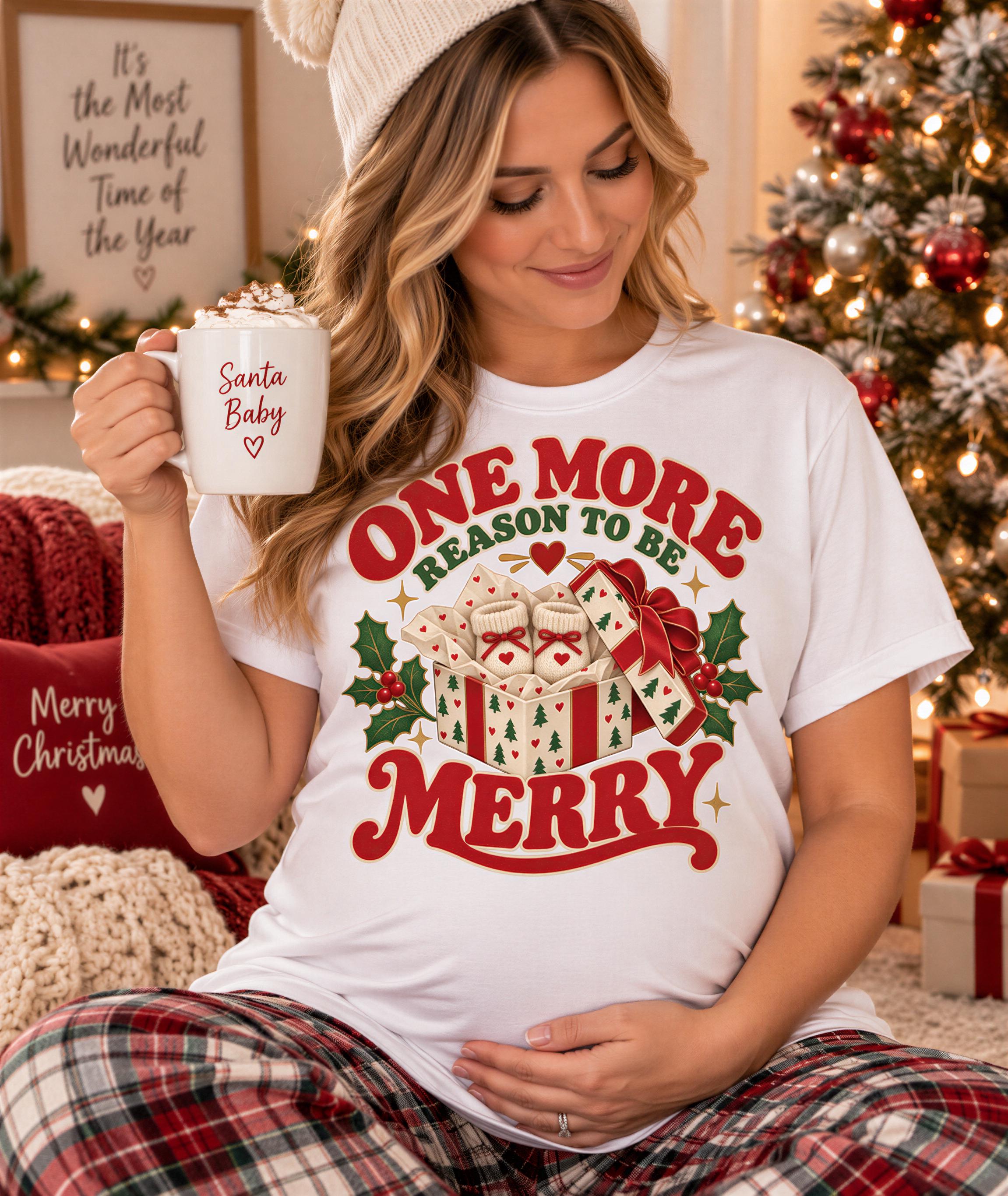 A woman wearing a Santa Baby t-shirt and holding a mug with a Christmas-themed design, smiling and sitting in front of a Christmas tree.