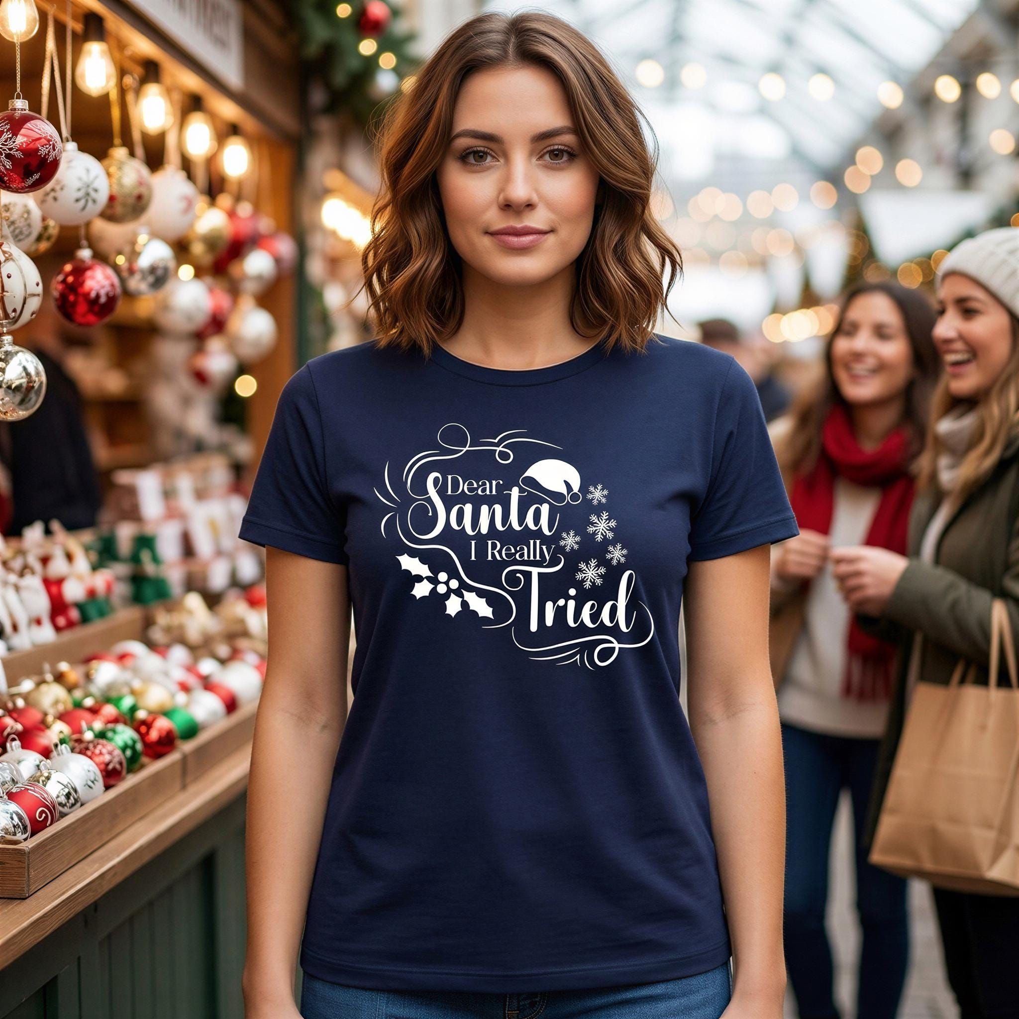 A woman wearing a navy blue t-shirt with a humorous text printed on it, standing in front of a Christmas market with other people visible in the background.