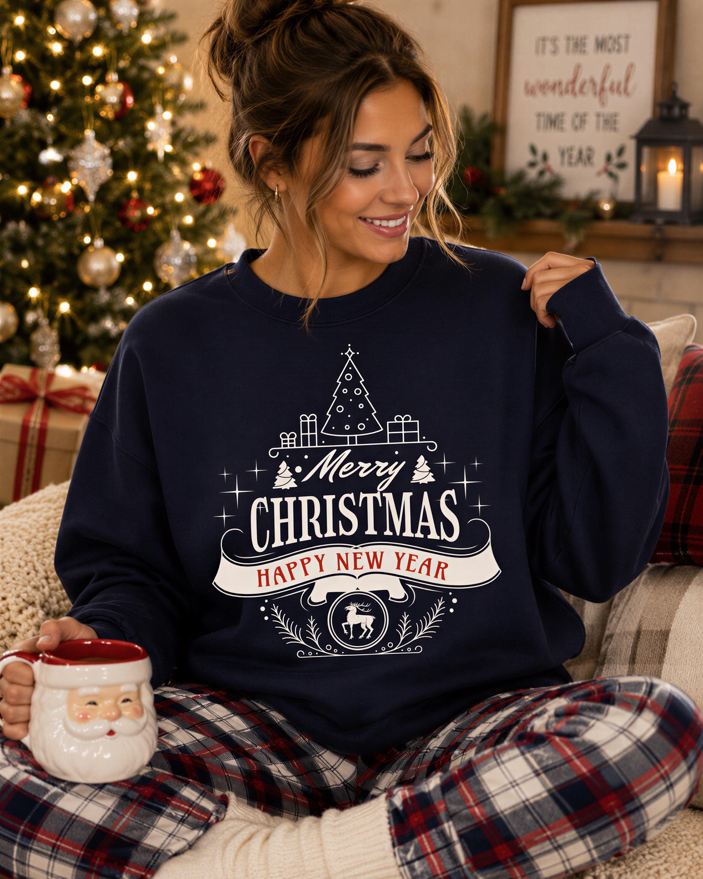 A woman wearing a navy blue sweatshirt with a Christmas-themed design is sitting on a couch, holding a mug and smiling.
