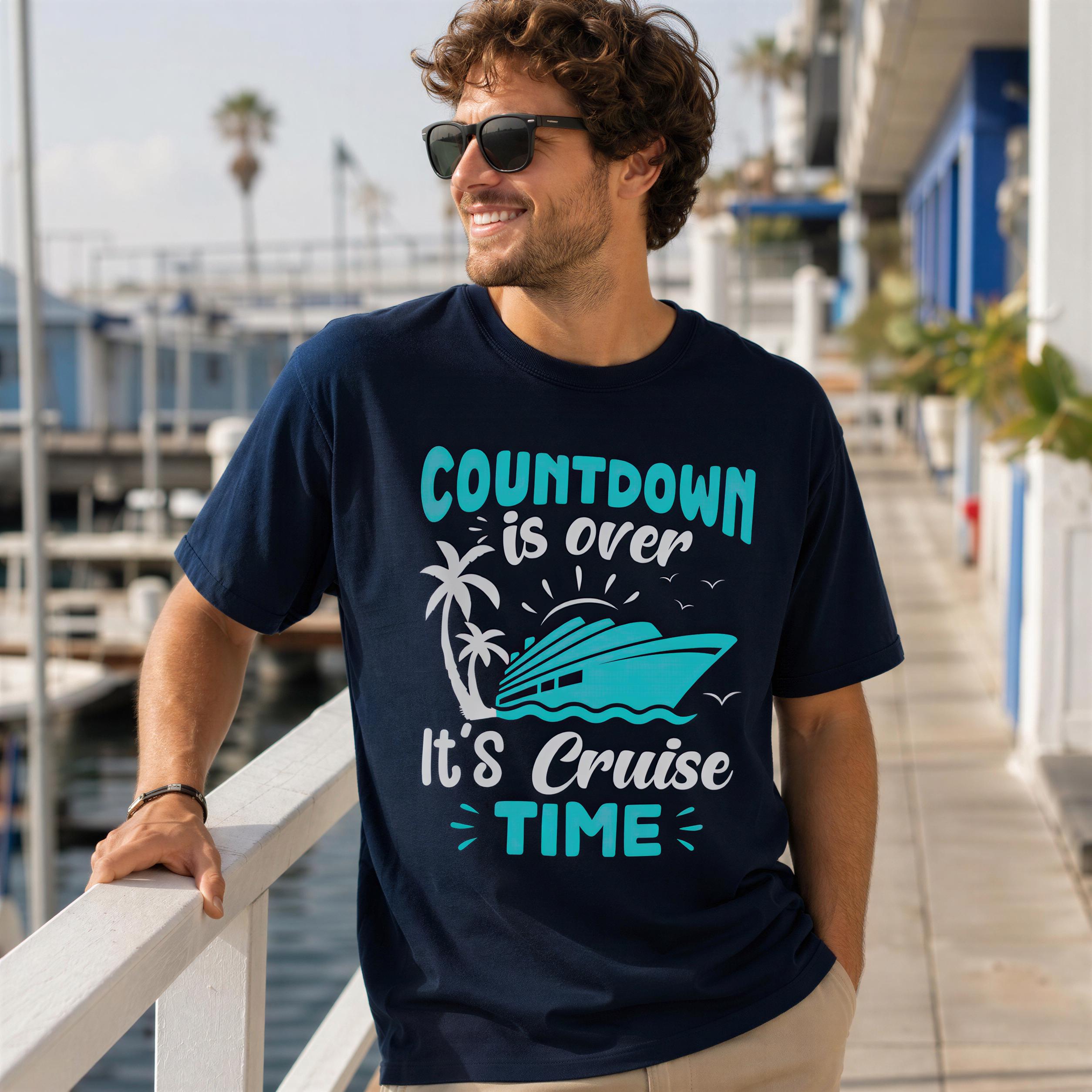 A man wearing a navy blue t-shirt with a graphic design and text, standing on a dock or pier overlooking the water.