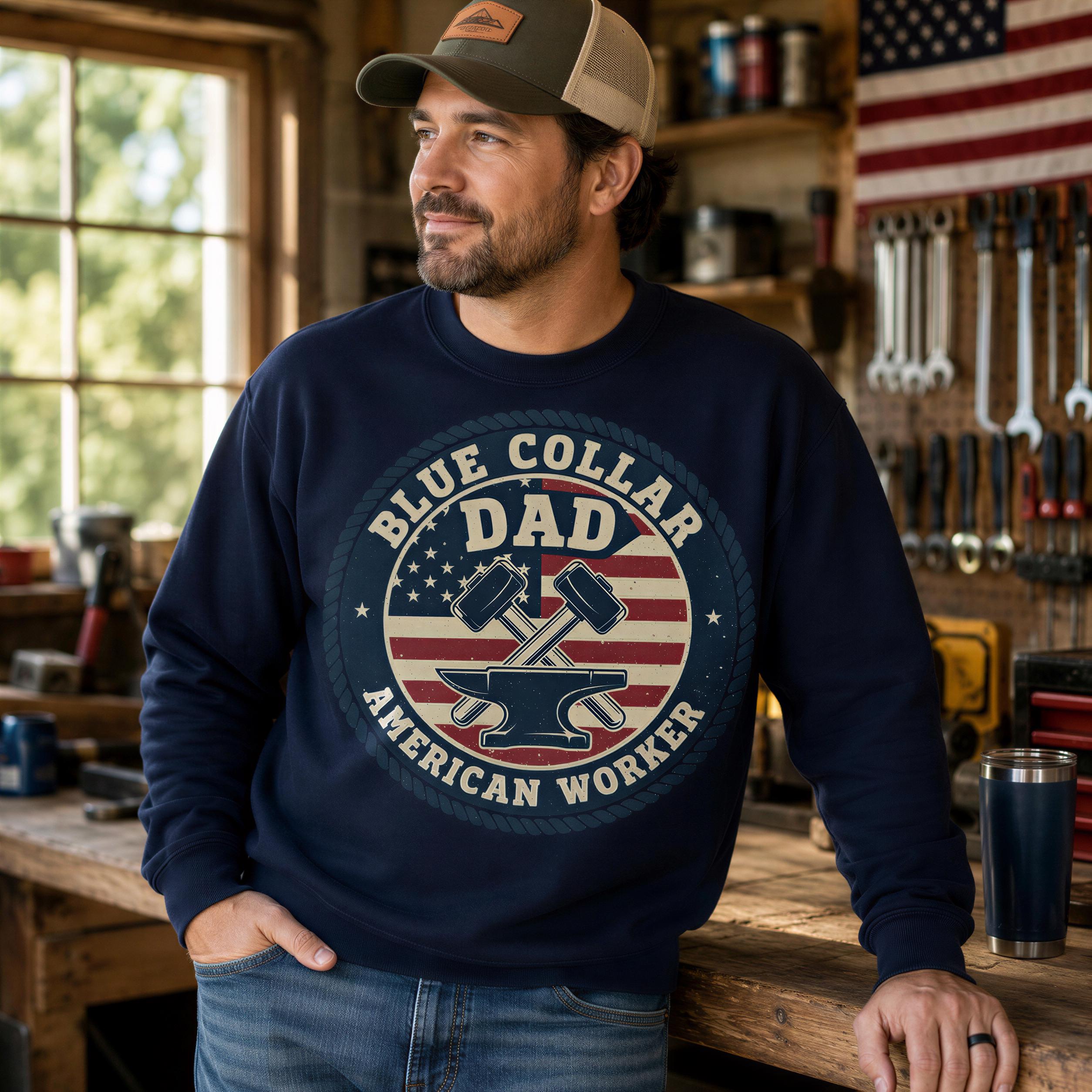 A man wearing a navy blue sweatshirt with a graphic design stands in a workshop surrounded by tools and equipment.