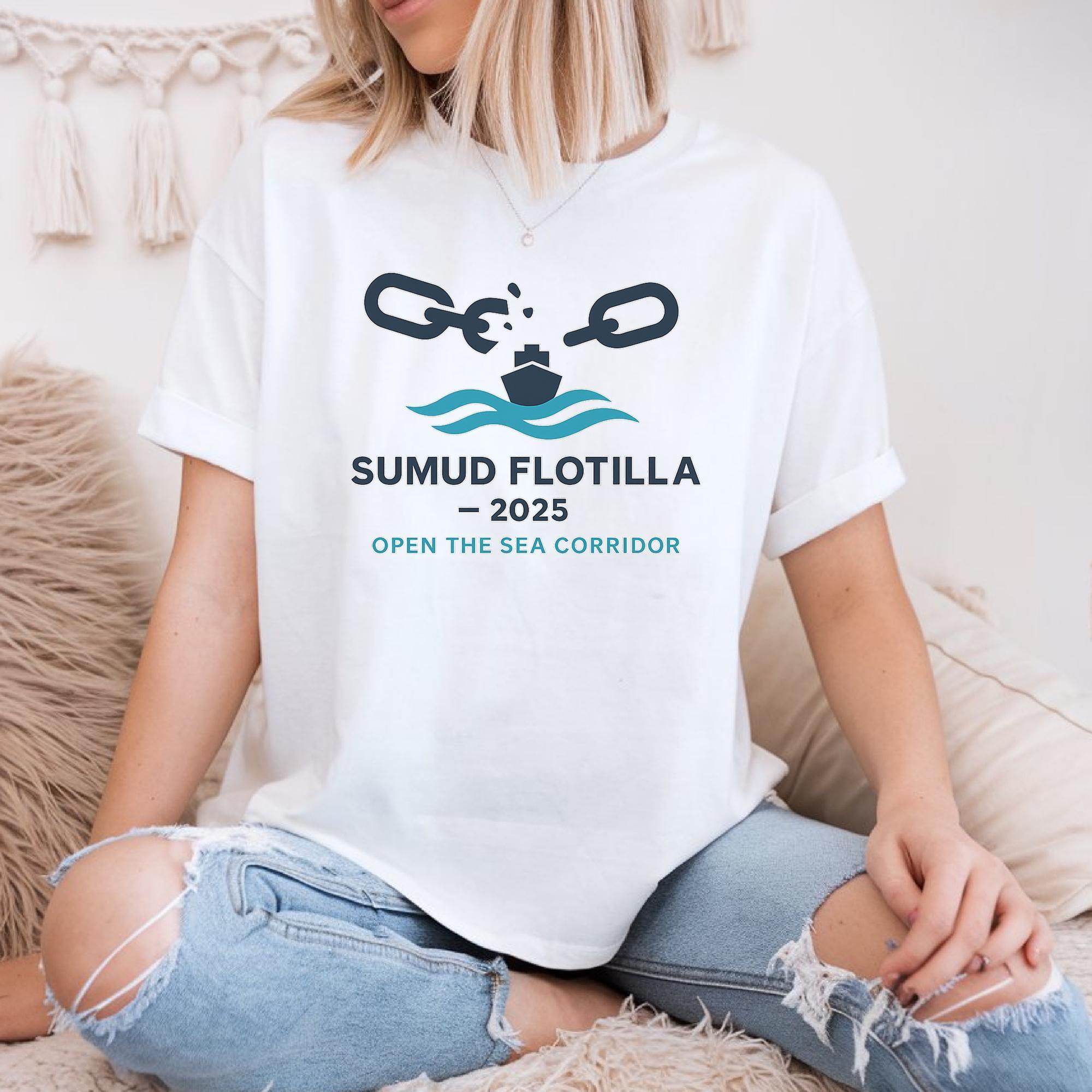 A woman wearing a white t-shirt with a graphic design and text, sitting on a couch.