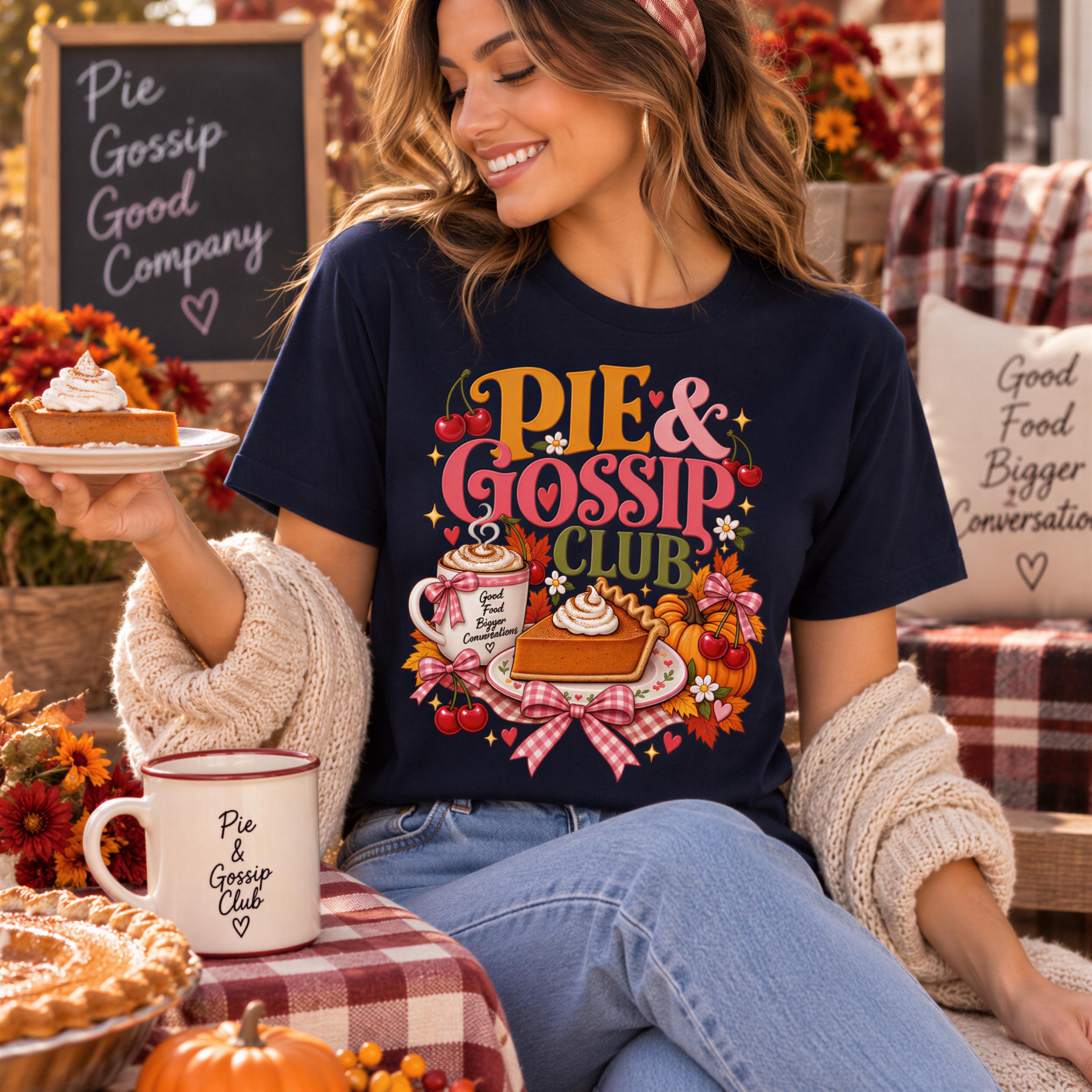 A woman wearing a black t-shirt with a colorful graphic of a pie and a cup of coffee, smiling and holding a plate of pie.