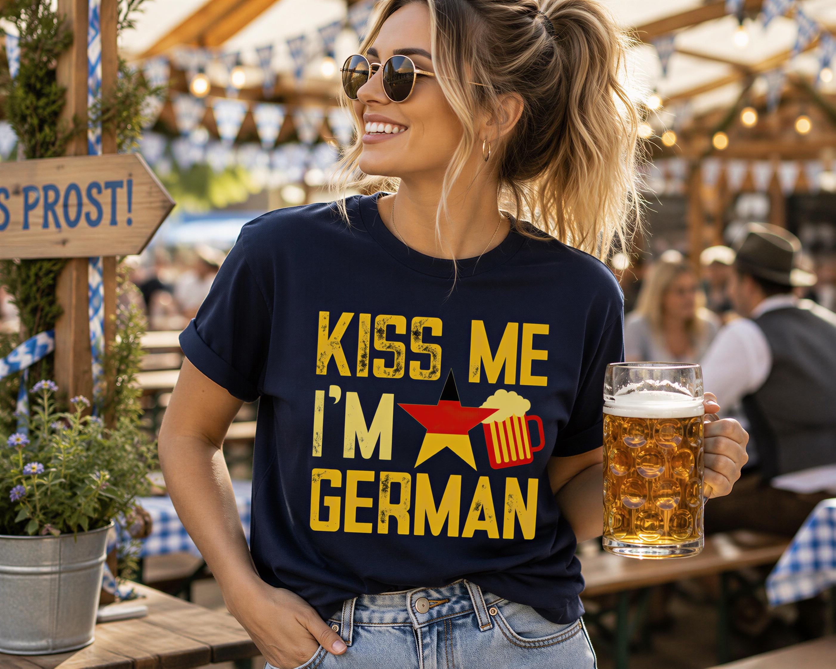 A woman wearing a blue t-shirt with a graphic and holding a glass of beer at an outdoor event.