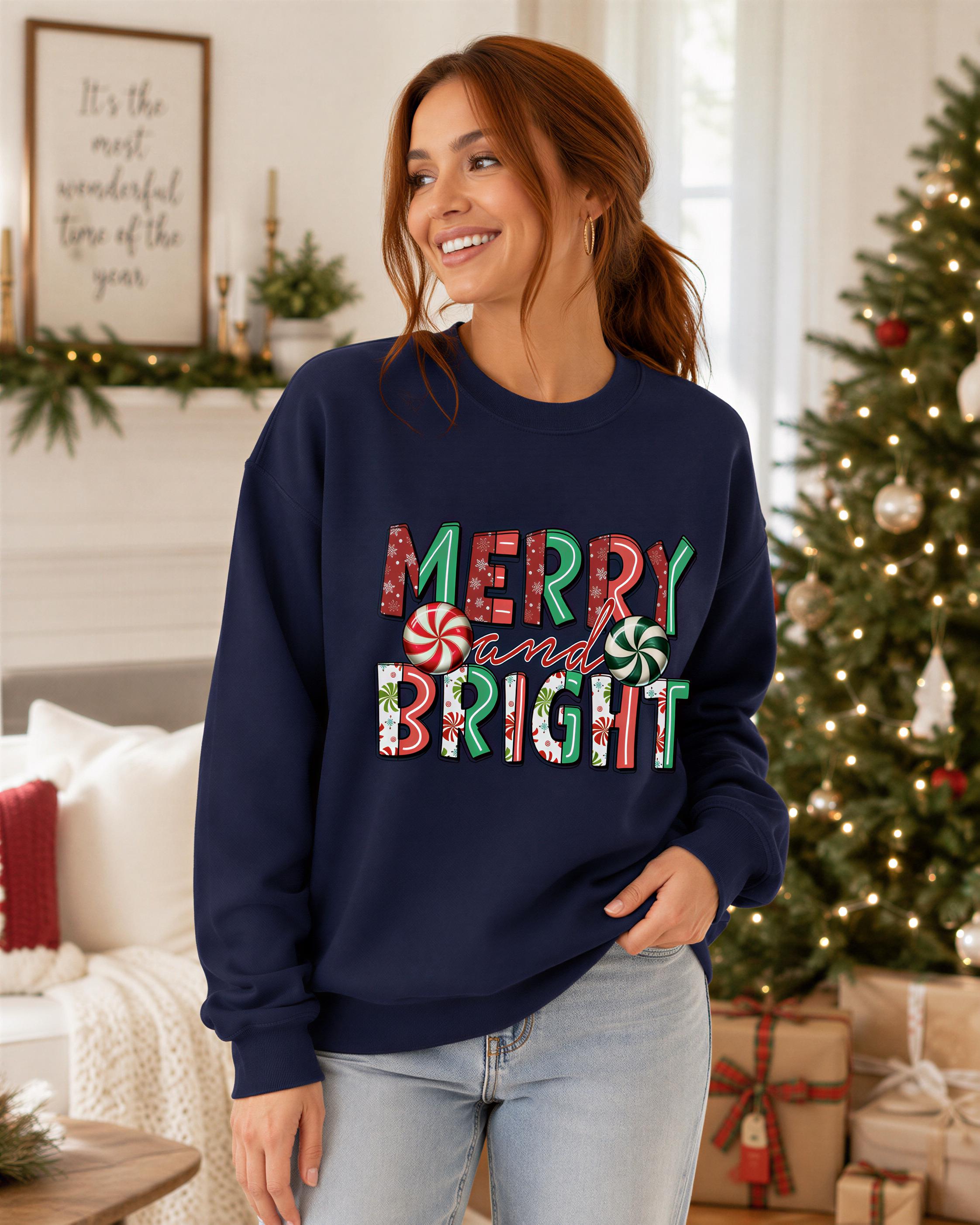 A woman wearing a navy blue sweatshirt with the text "MERRY AND BRIGHT" stands in front of a Christmas tree and a fireplace.