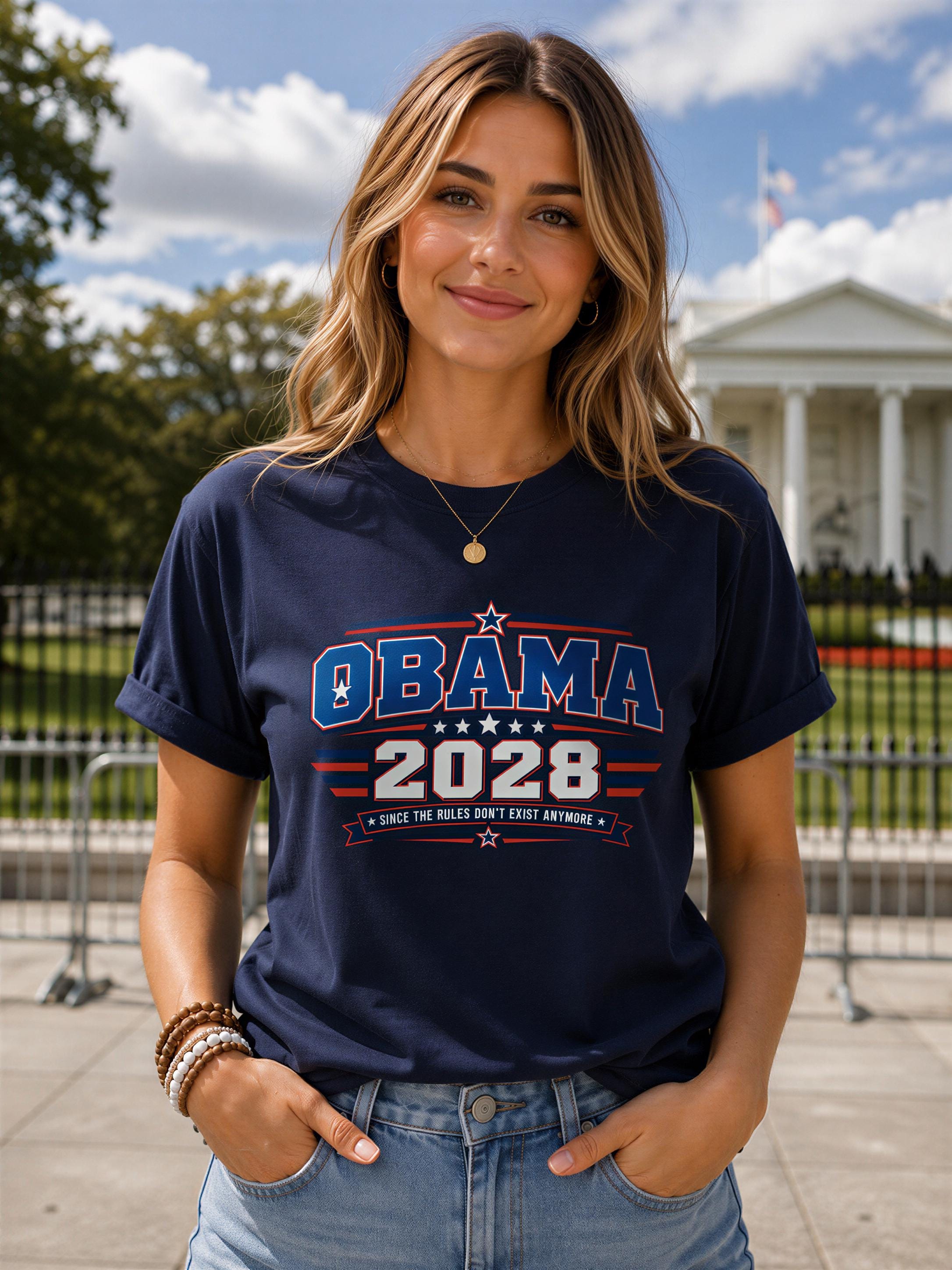 A woman wearing a navy blue t-shirt with the text "OBAMA 2028" and "SINCE THE RULES DON'T EXIST ANYWAY" printed on it, standing in front of the White House.