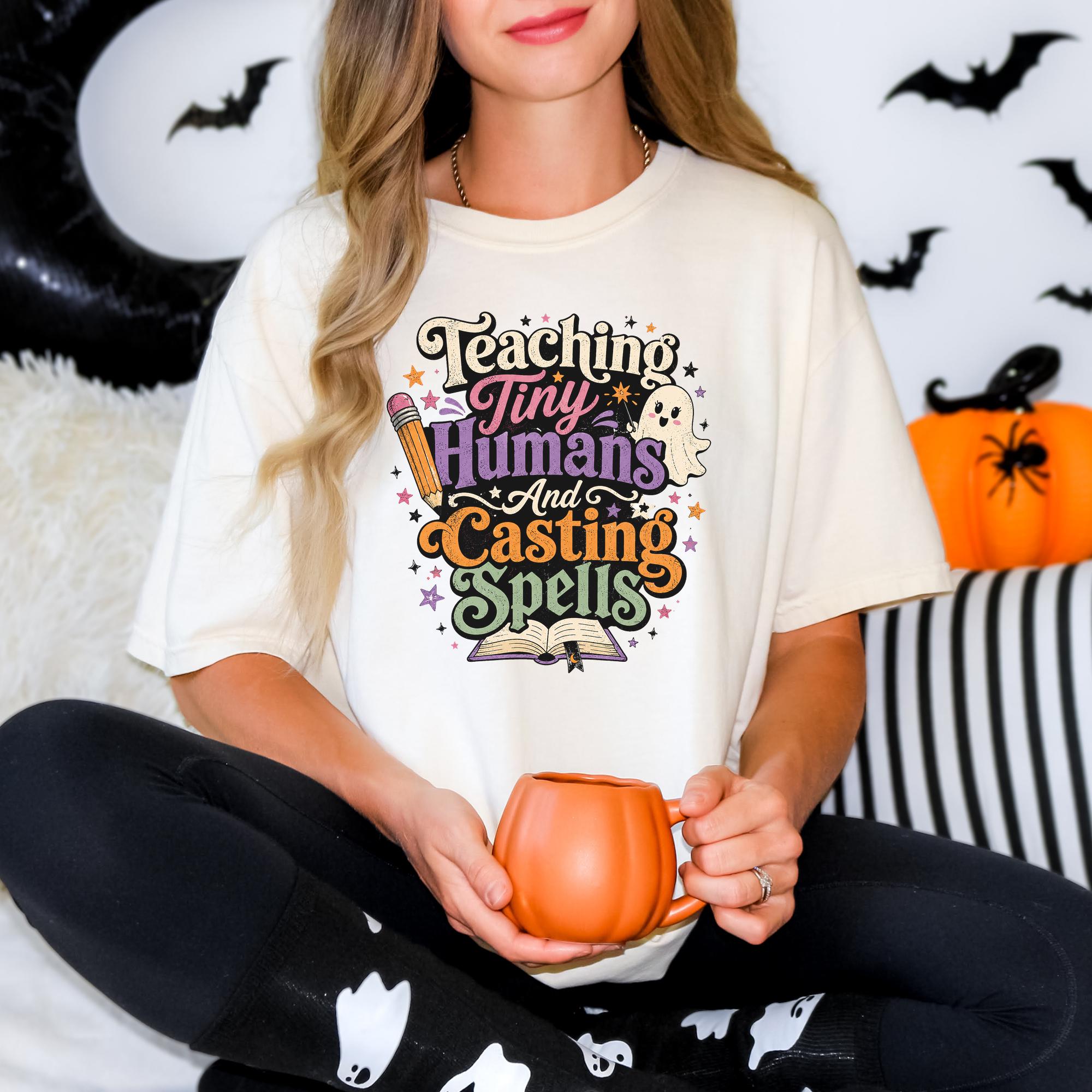 A woman wearing a white t-shirt with a colorful graphic design and holding a pumpkin-shaped mug.