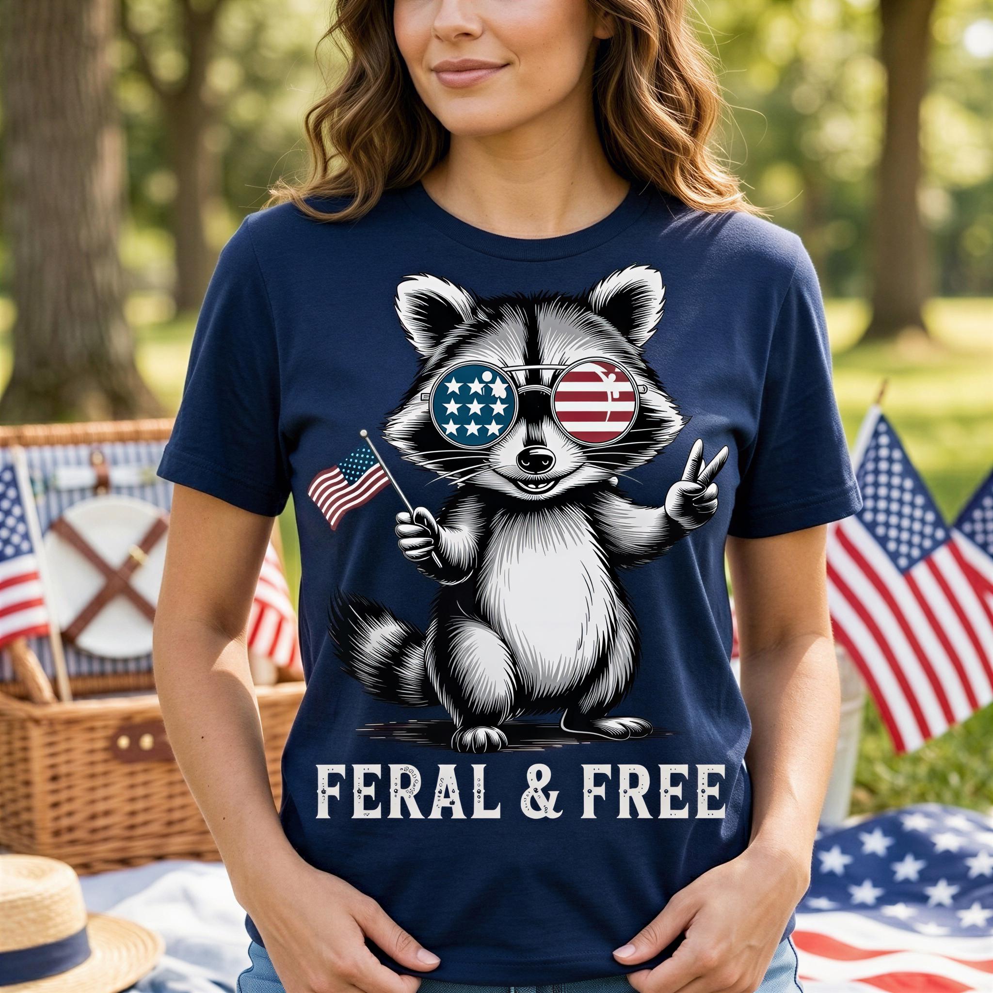 A woman wearing a blue t-shirt with a graphic of a raccoon wearing sunglasses and holding an American flag, with the text "Feral & Free" below the image.