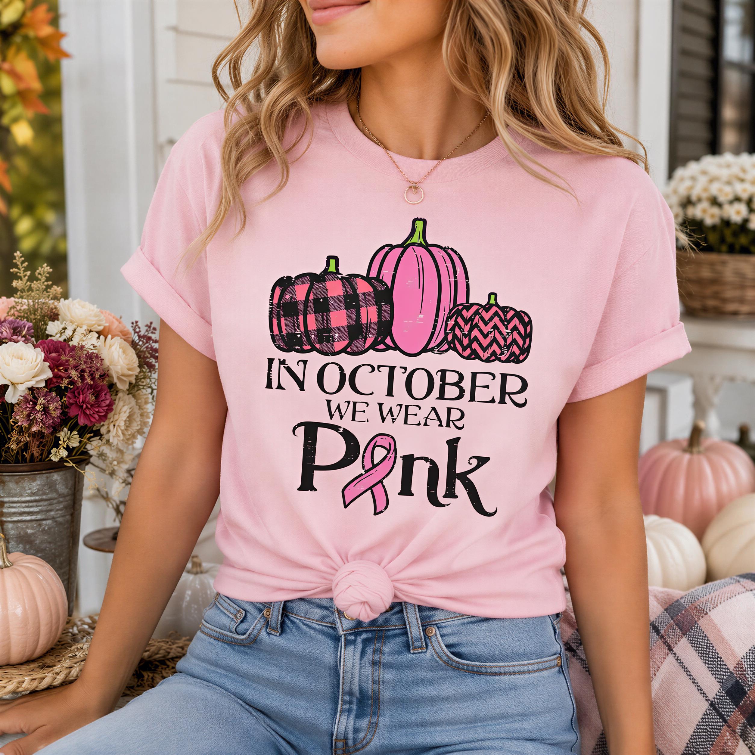 A woman wearing a pink t-shirt with a graphic of pumpkins and a pink ribbon, sitting on a porch surrounded by flowers.