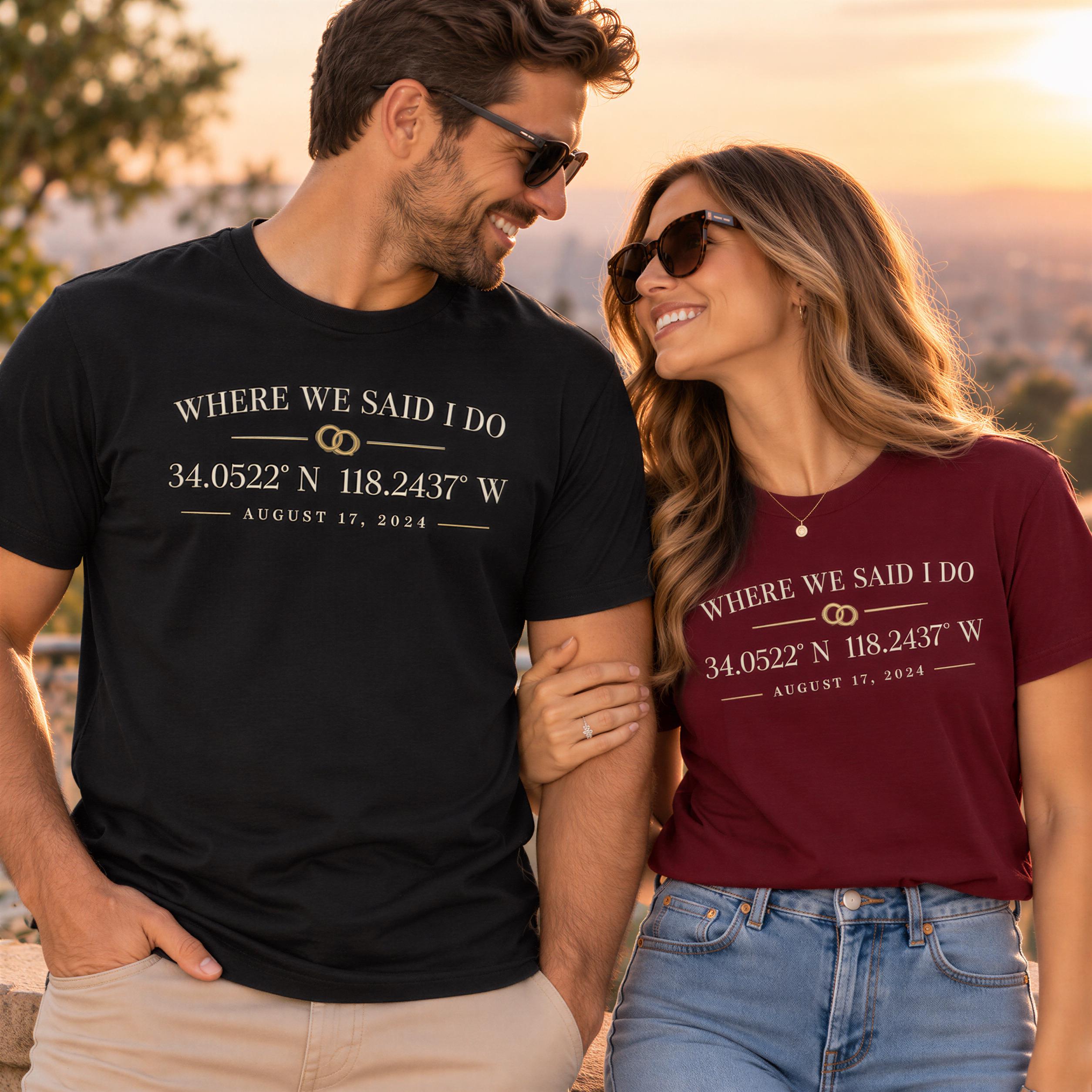 A man and a woman standing together, both wearing matching t-shirts with the text "WHERE WE SAID I DO 34.0522 N 118.2437 W AUGUST 17, 1924" printed on them.