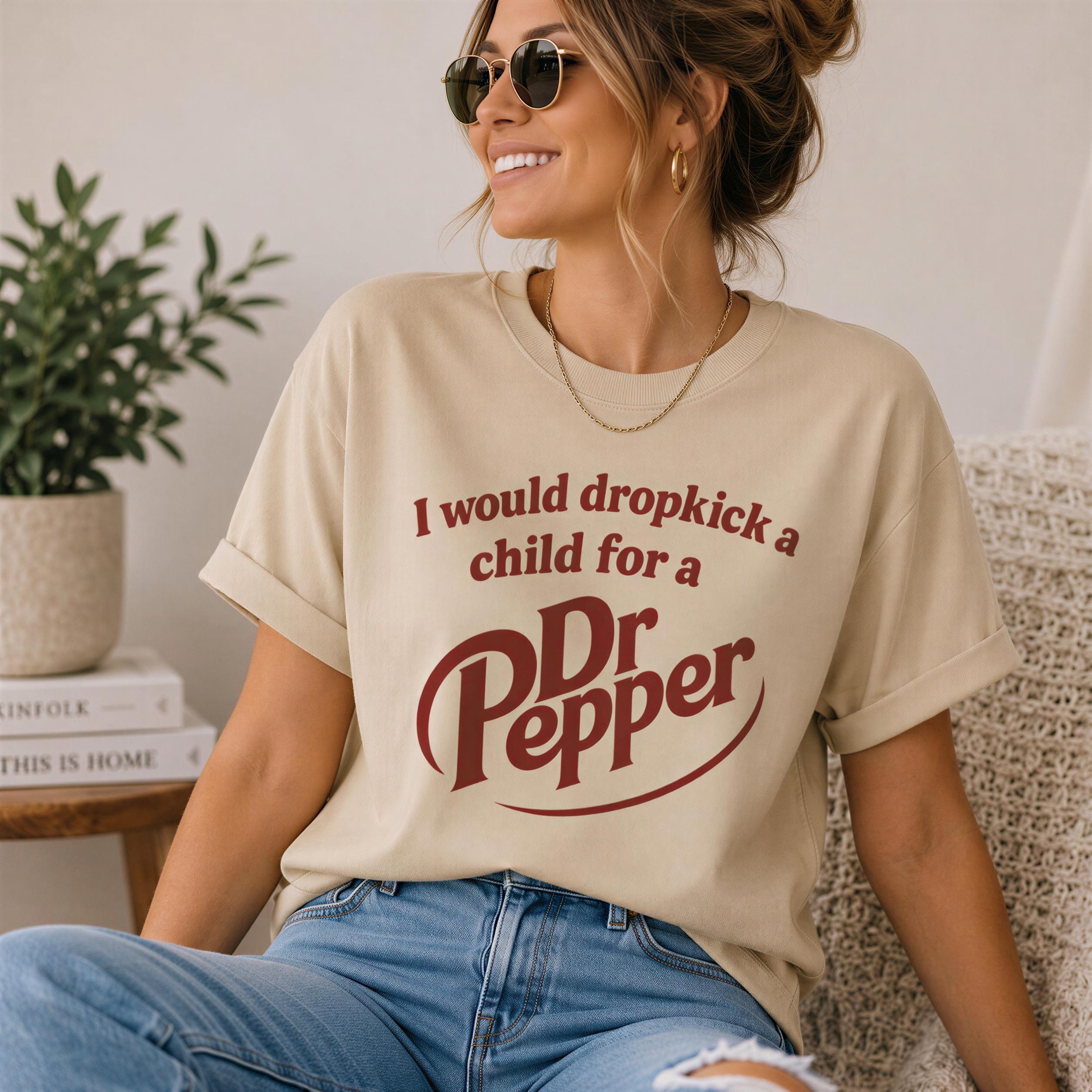 A woman wearing a beige t-shirt with a red text design and sunglasses is sitting on a couch, smiling.