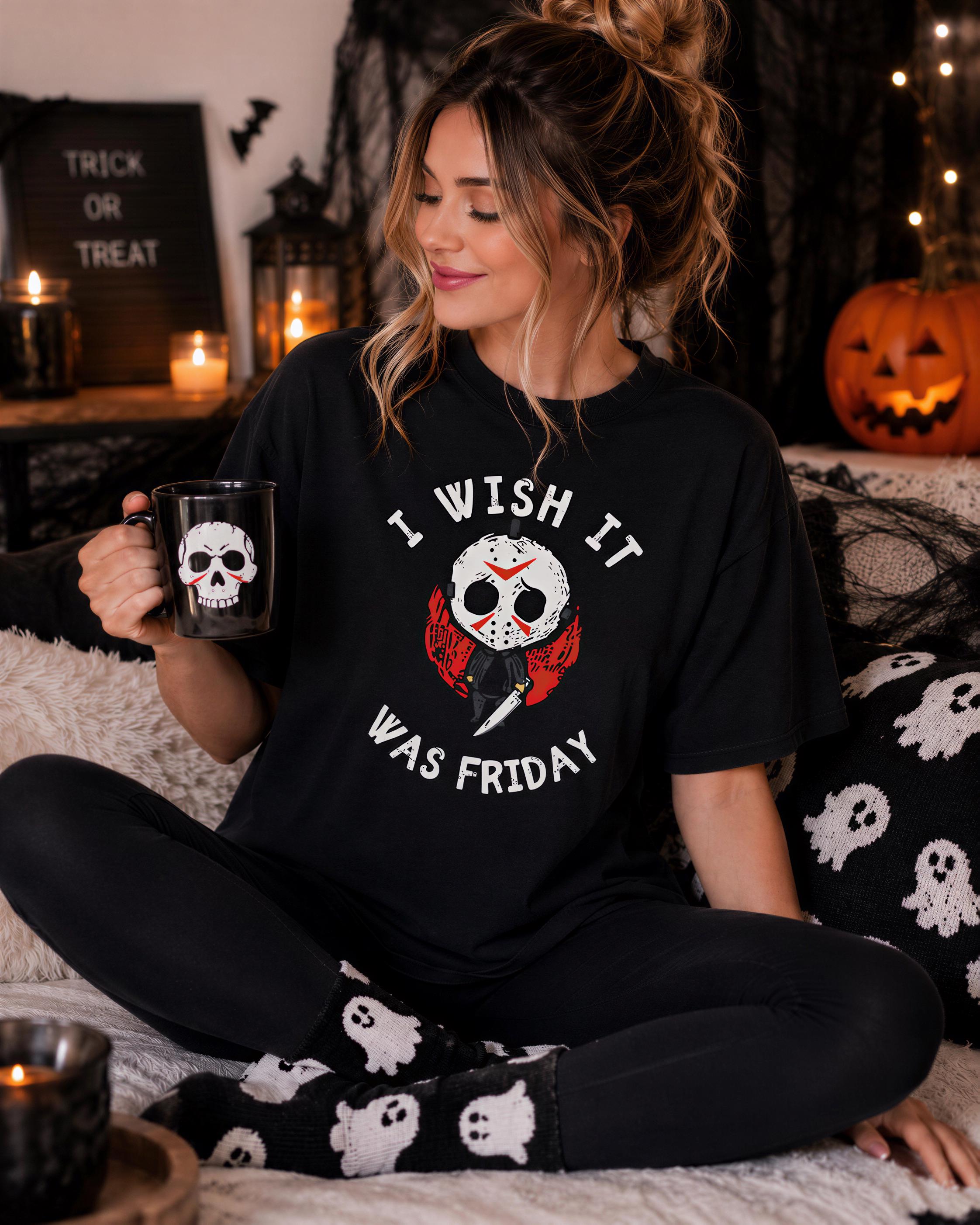 A woman wearing a black t-shirt with a Halloween-themed graphic and text, sitting on a couch with a pumpkin and other Halloween decorations in the background.