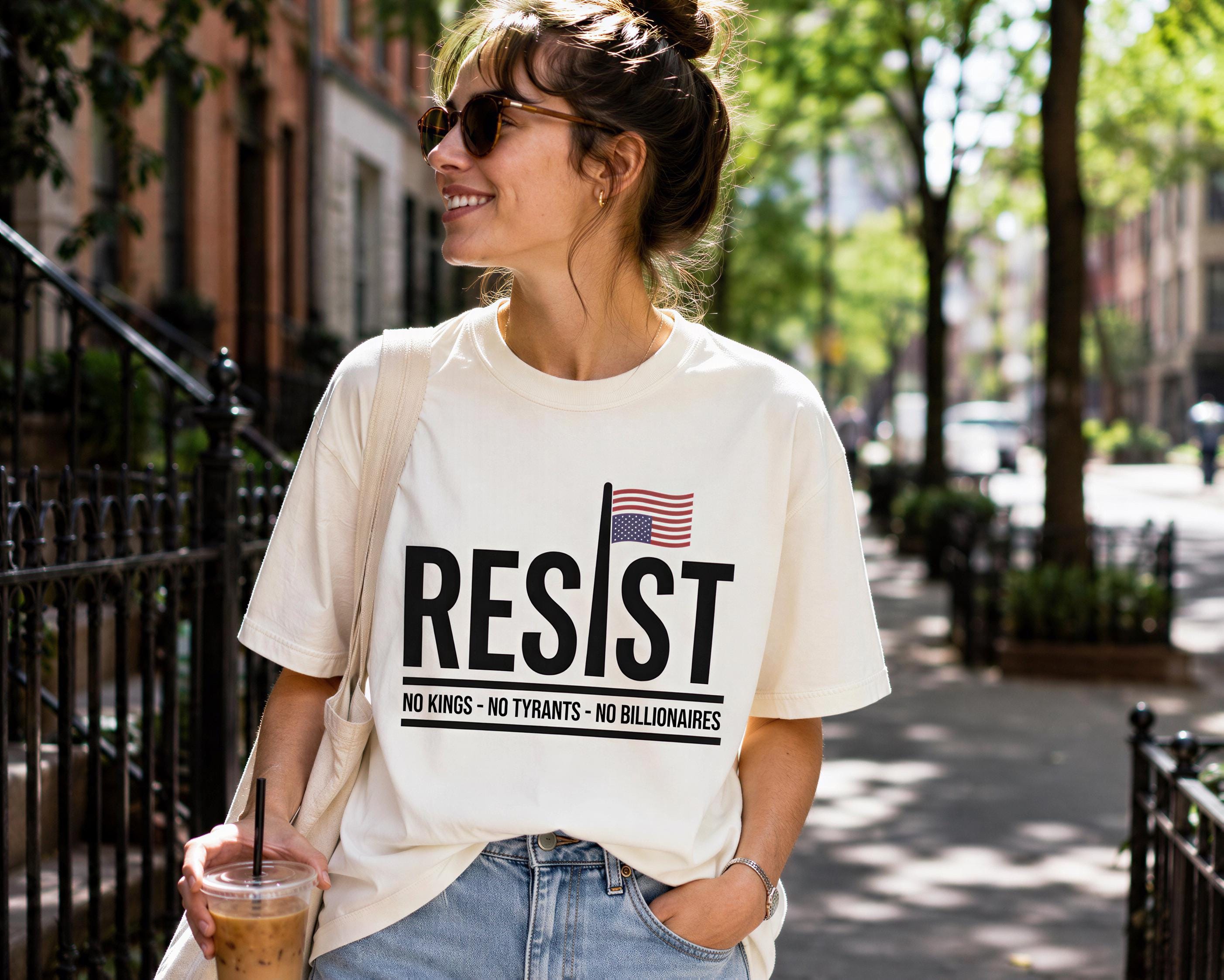 A woman wearing a white t-shirt with the text "RESIST" and an American flag, holding a drink and smiling.