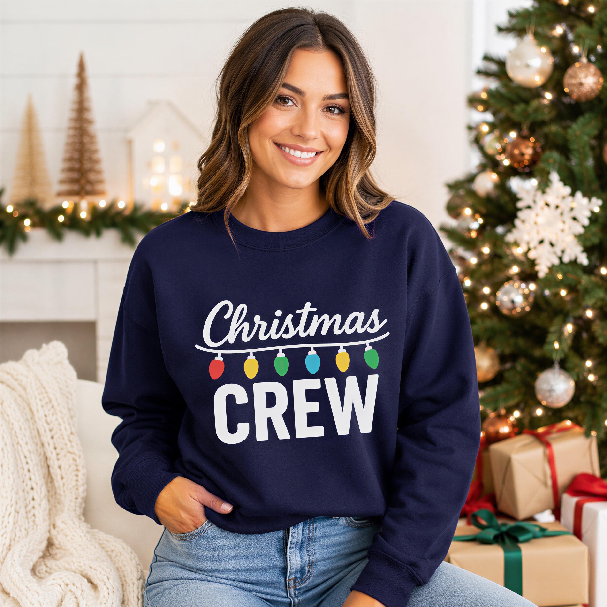A woman wearing a navy blue sweatshirt with the text "Christmas Crew" is sitting in front of a Christmas tree and presents.