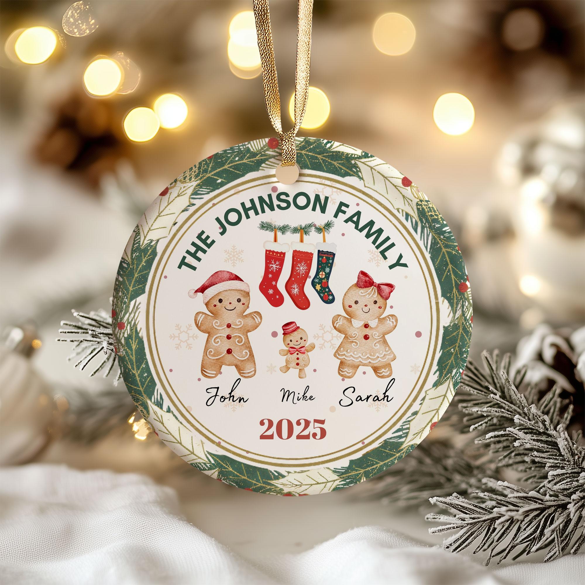 A Christmas ornament with a family tree design, featuring gingerbread men and a snowman. The ornament is hanging from a string and is surrounded by pine branches.