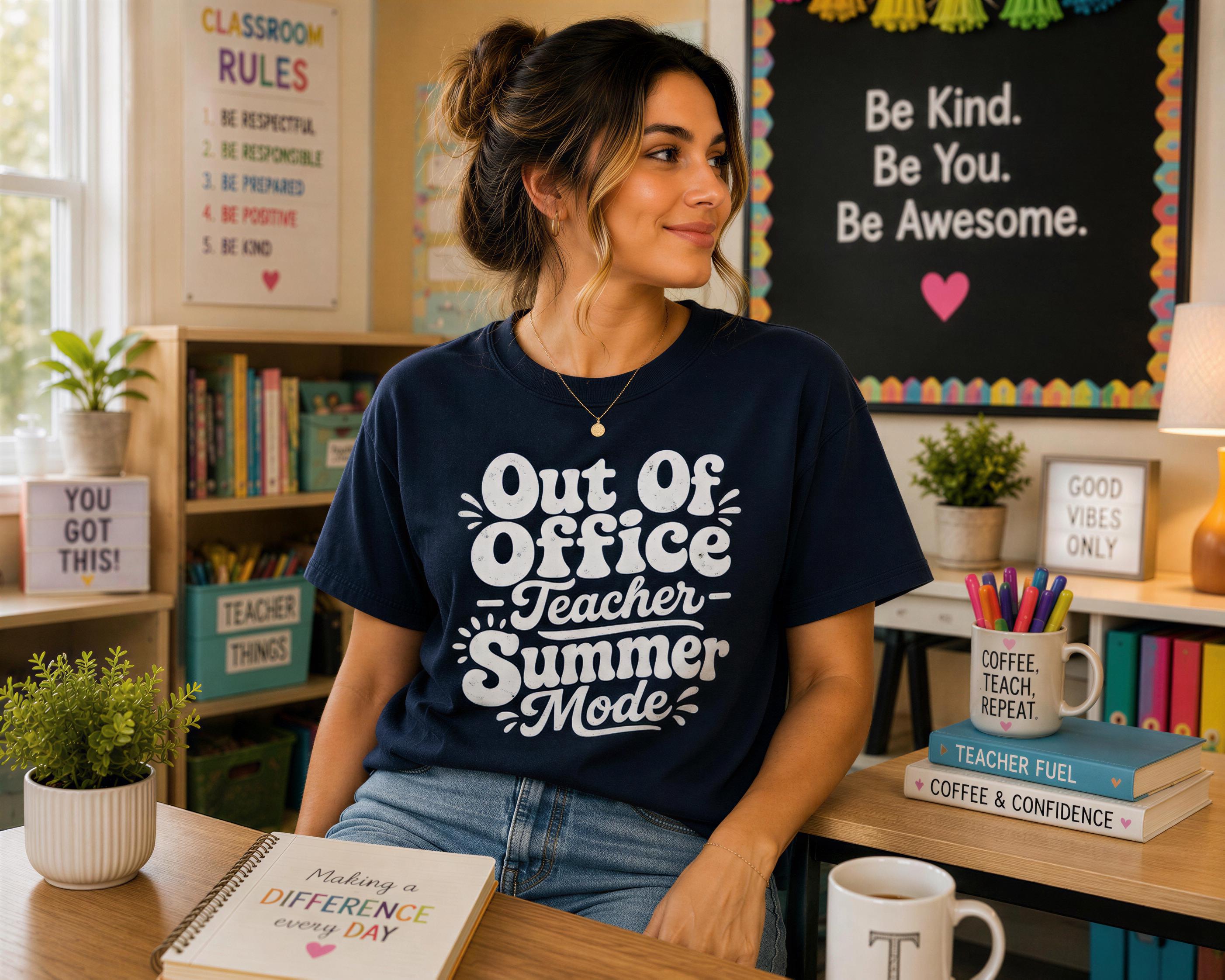 A woman wearing a blue t-shirt with text and smiling at the camera, sitting at a desk with a notebook and coffee mug in front of her.