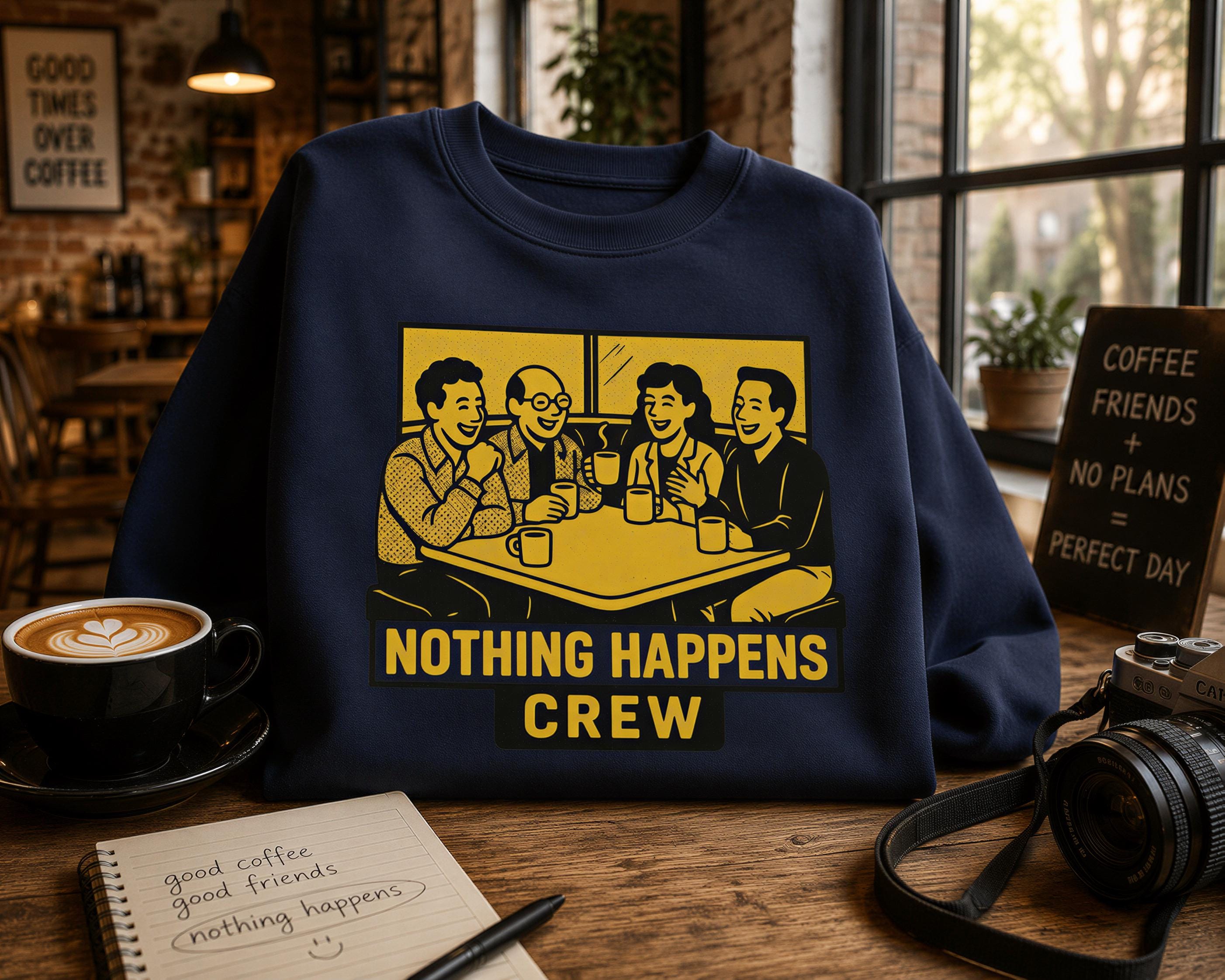 a navy blue sweatshirt with a yellow graphic design depicting four people sitting at a table, smiling and enjoying coffee together. The text on the sweatshirt reads "Nothing Happens Crew". The sweatshirt is displayed on a wooden table, along with a cup of coffee, a notebook, and a camera.