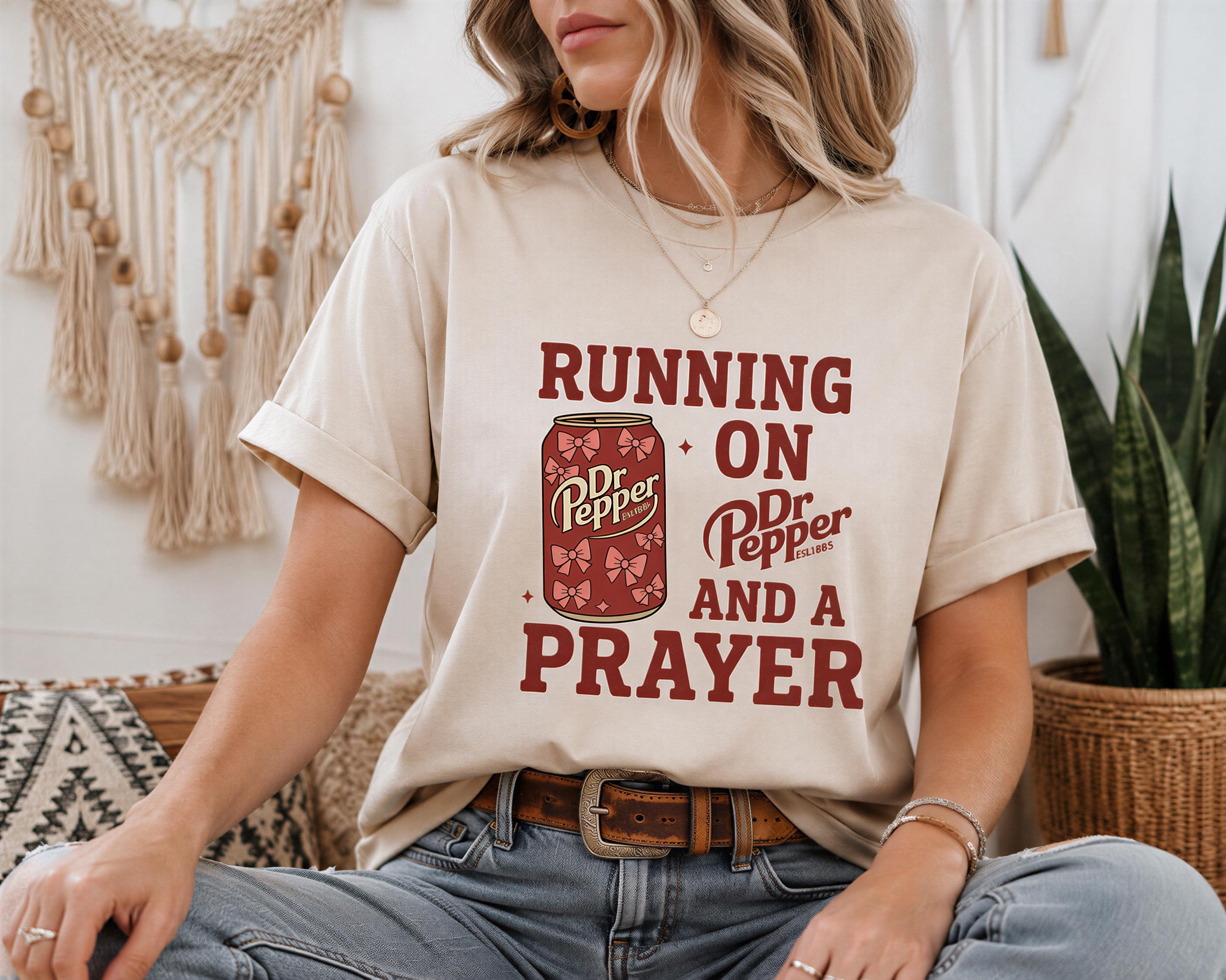 A woman wearing a t-shirt with a graphic design and text, sitting in a casual setting with plants in the background.