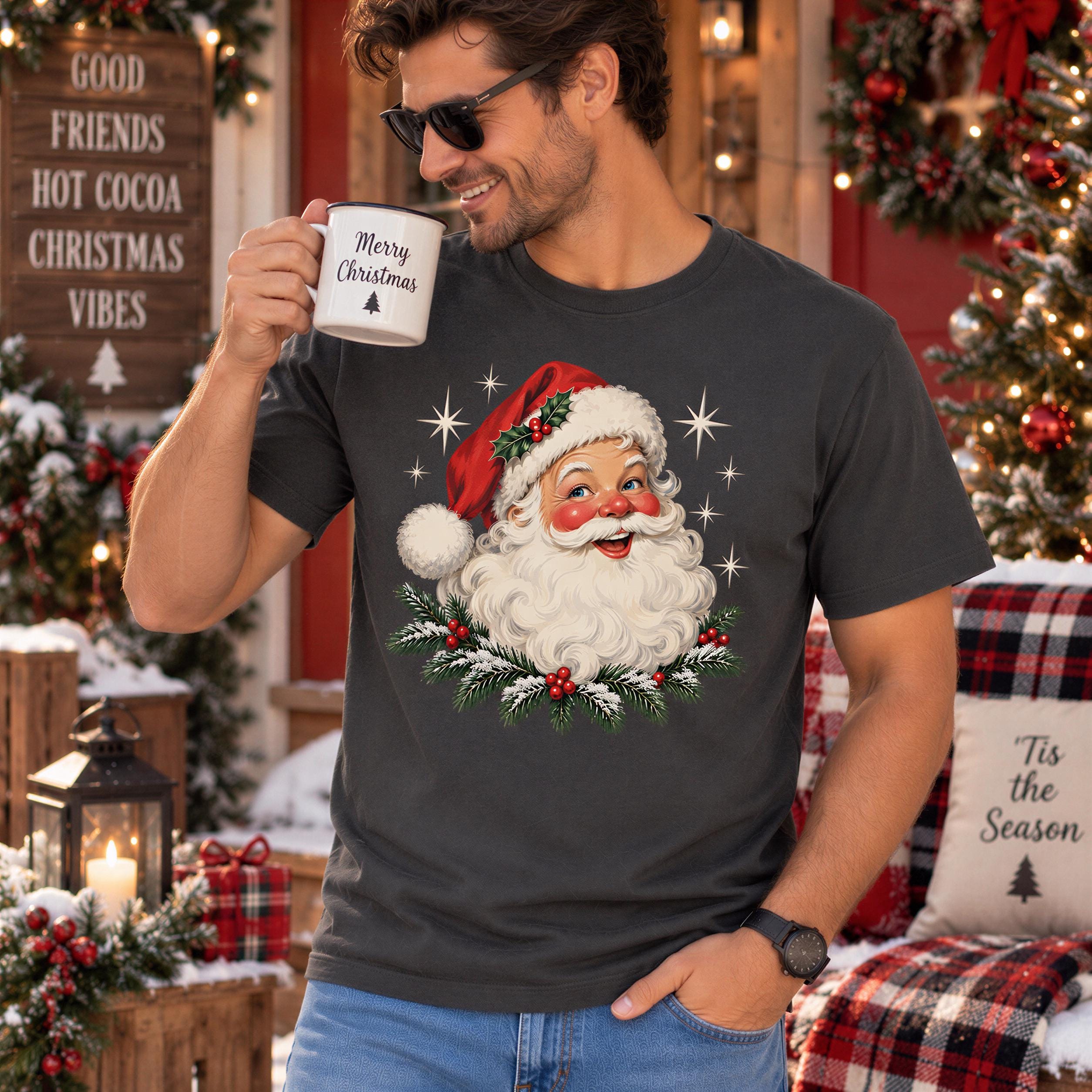 A man wearing a t-shirt with a Santa Claus design and holding a mug is standing in front of a Christmas tree and wreaths.