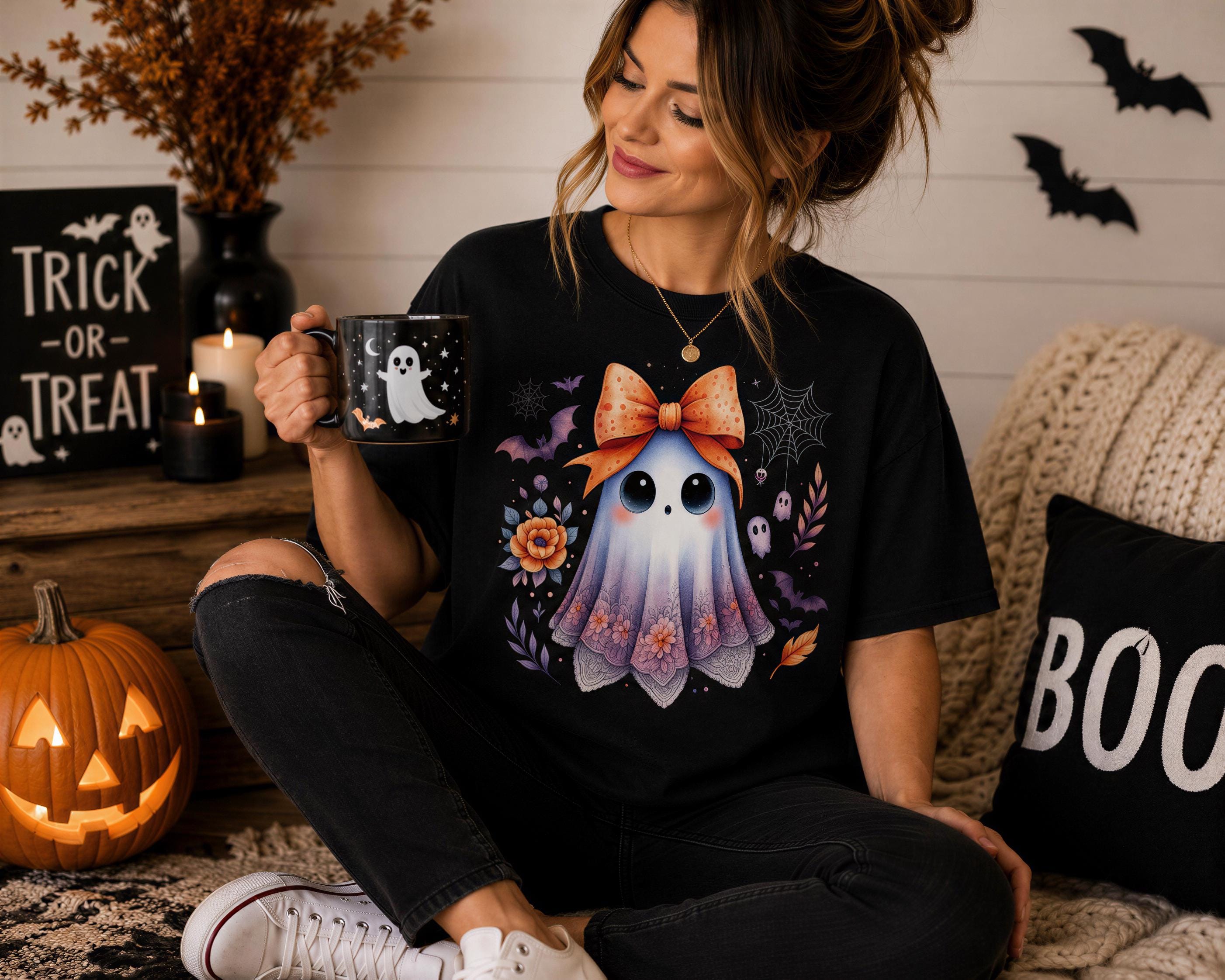 A woman is sitting on a couch, holding a mug with a Halloween-themed design featuring a ghost and a bow. The couch is decorated with Halloween-themed pillows and a carved pumpkin is visible in the background.