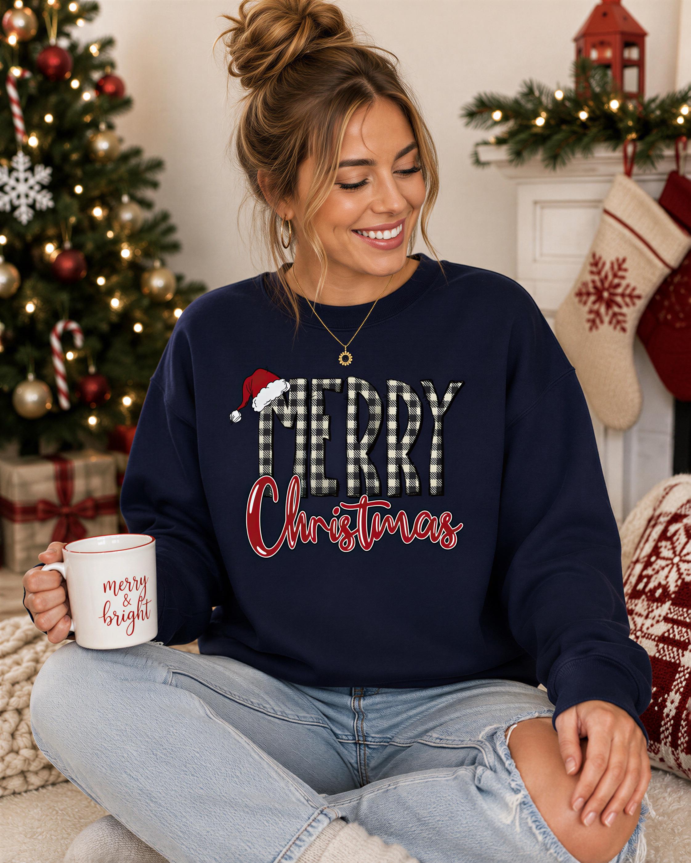 A woman wearing a navy blue sweatshirt with the text "MERRY CHRISTMAS" is sitting on the floor, holding a mug with the text "merry bright" written on it. In the background, there is a Christmas tree and stockings.