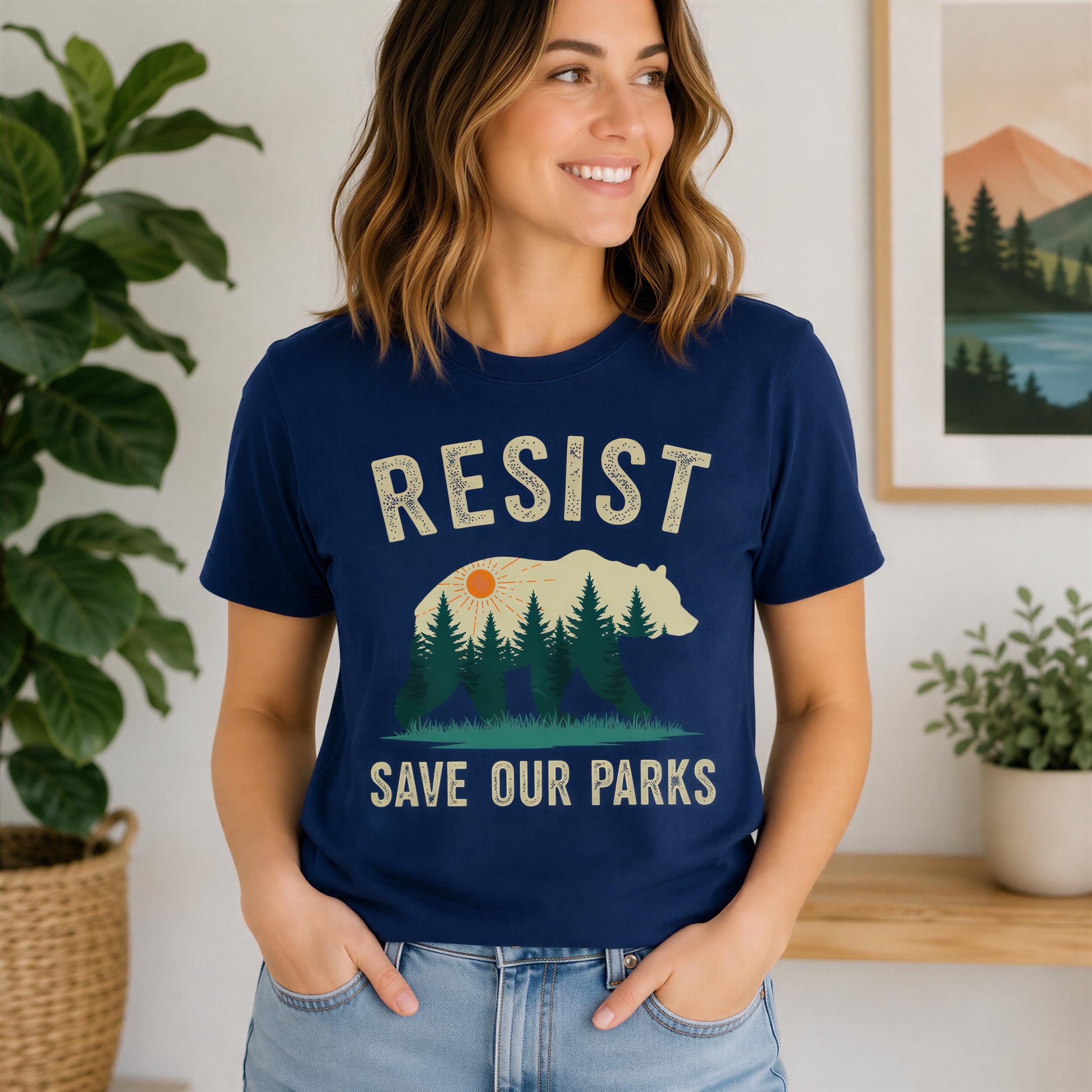 A woman wearing a blue t-shirt with the text "RESIST SAVE OUR PARKS" printed on it, smiling at the camera.