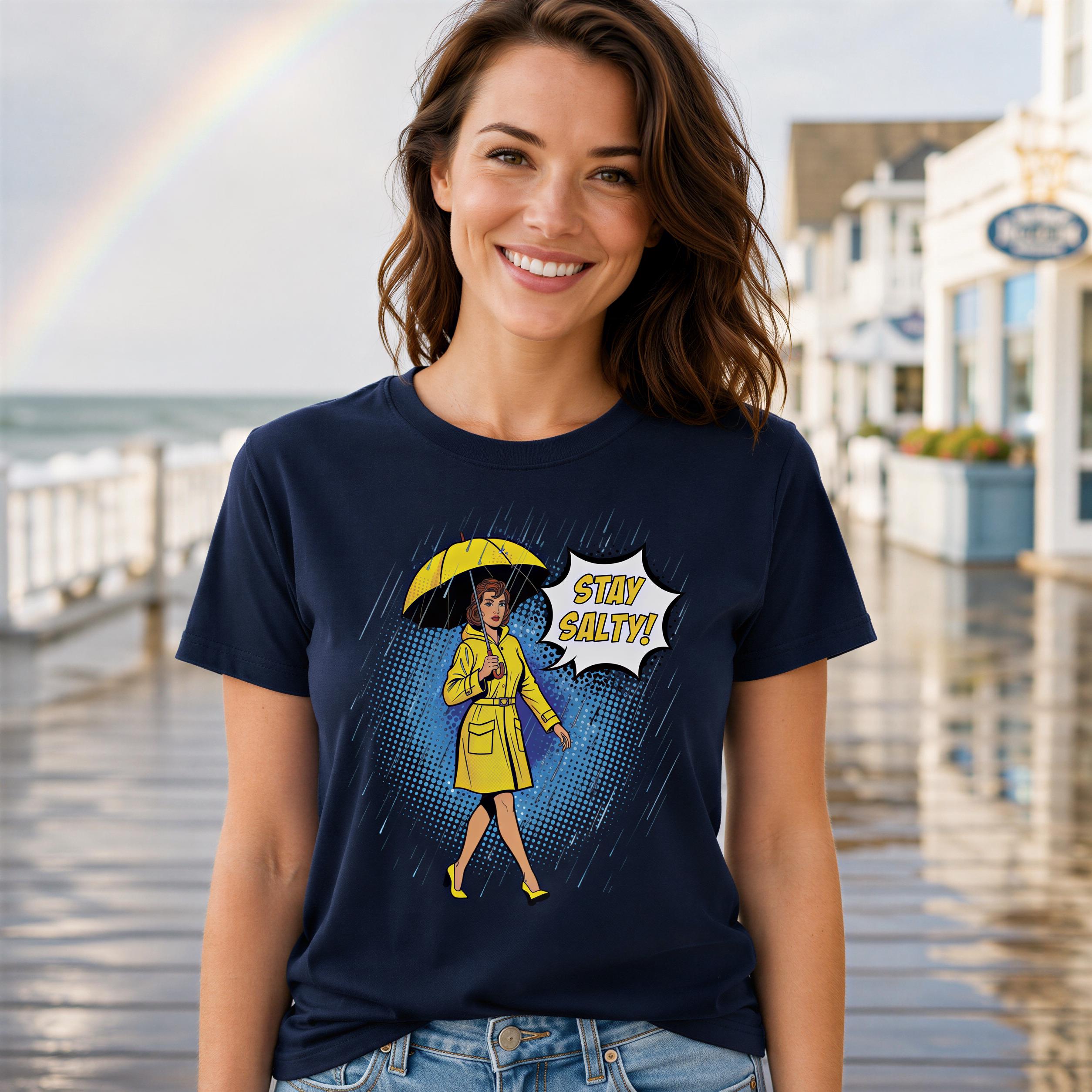 A woman wearing a yellow raincoat and holding an umbrella, with a graphic on her t-shirt that says "STAY SALTY!"