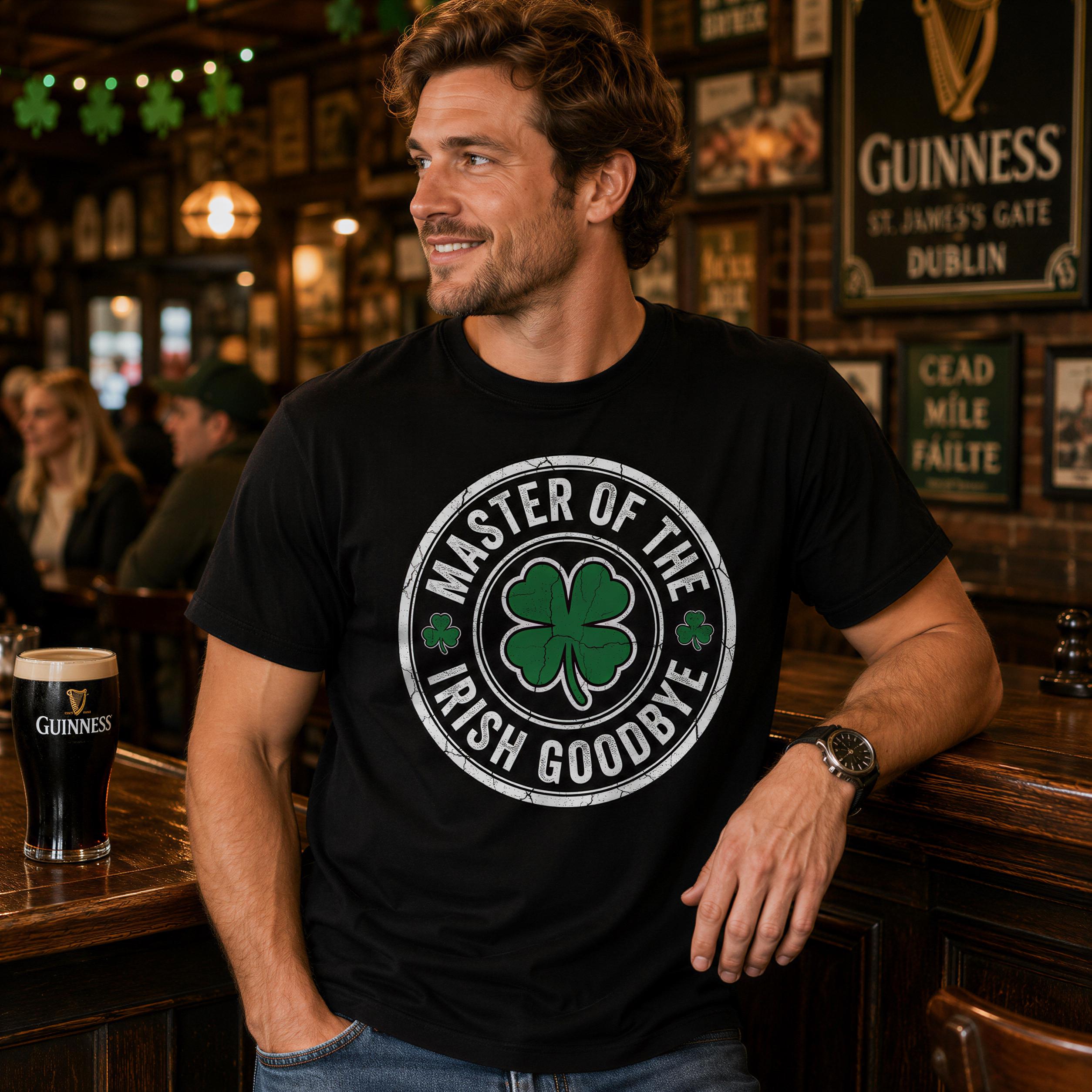A man wearing a black t-shirt with a white and green design is sitting at a bar, smiling and holding a glass of beer.