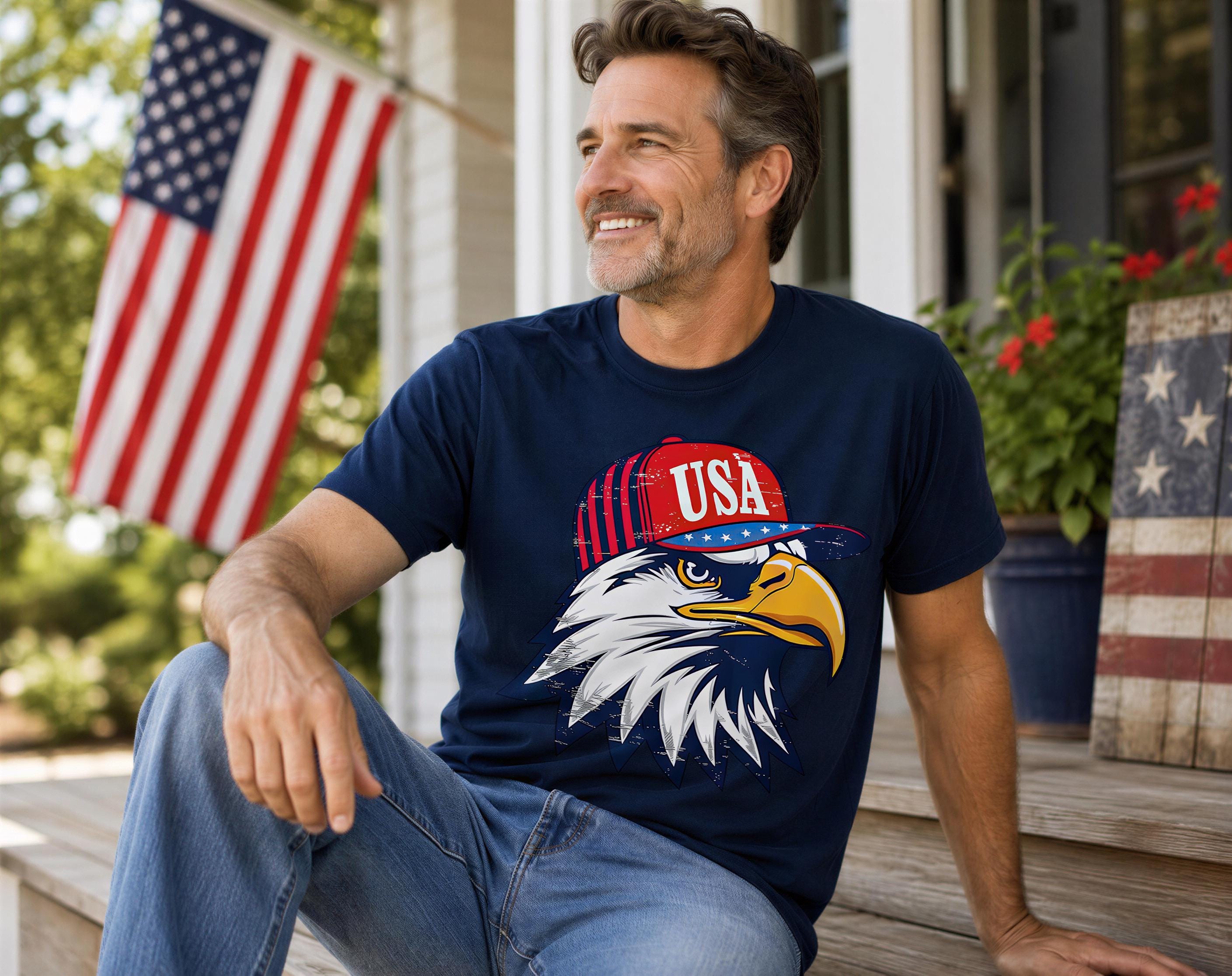A man wearing a blue t-shirt with an eagle wearing a hat and the word "USA" is sitting on a porch, smiling and looking towards the camera.