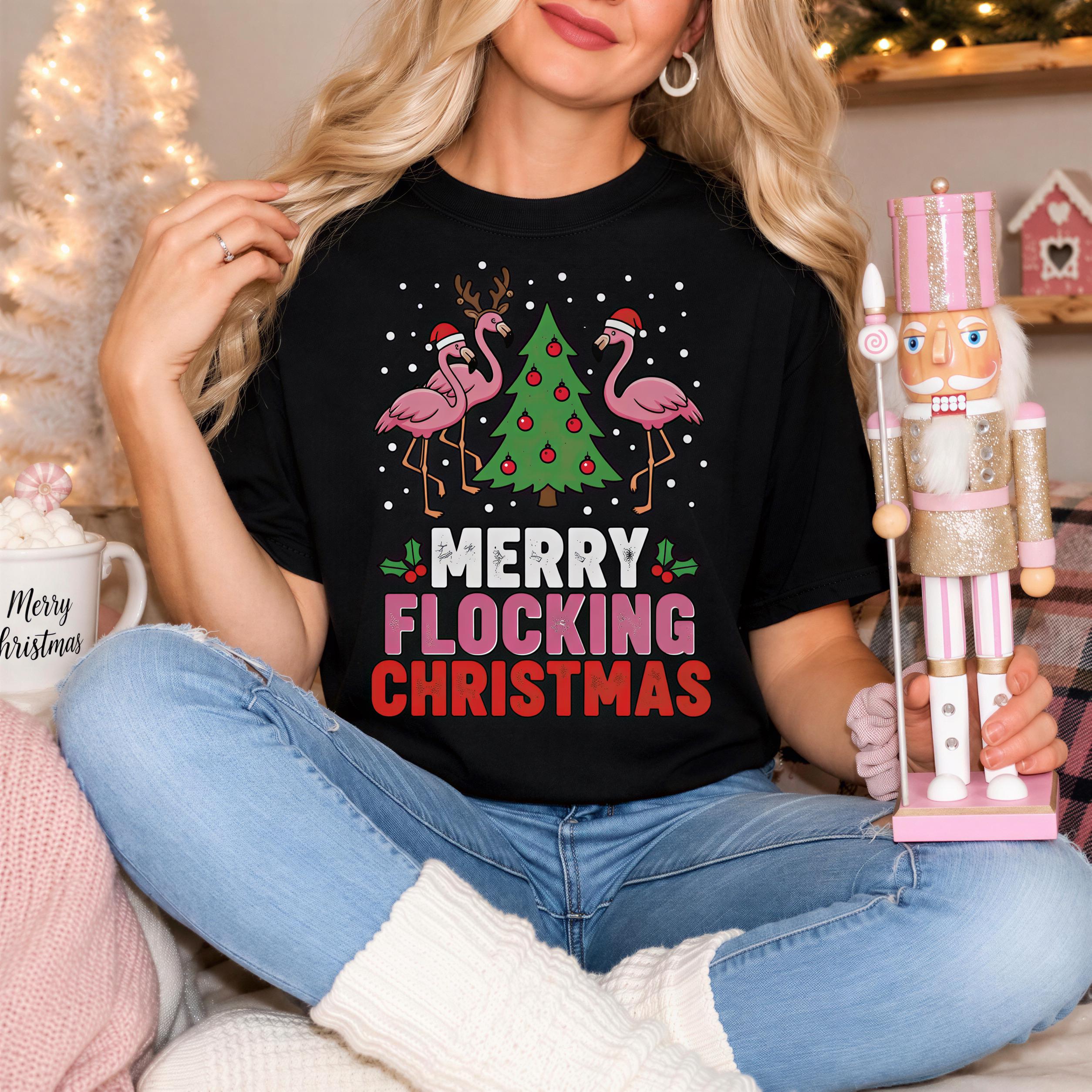 A woman wearing a black t-shirt with a Christmas-themed design and holding a nutcracker and a Christmas tree.